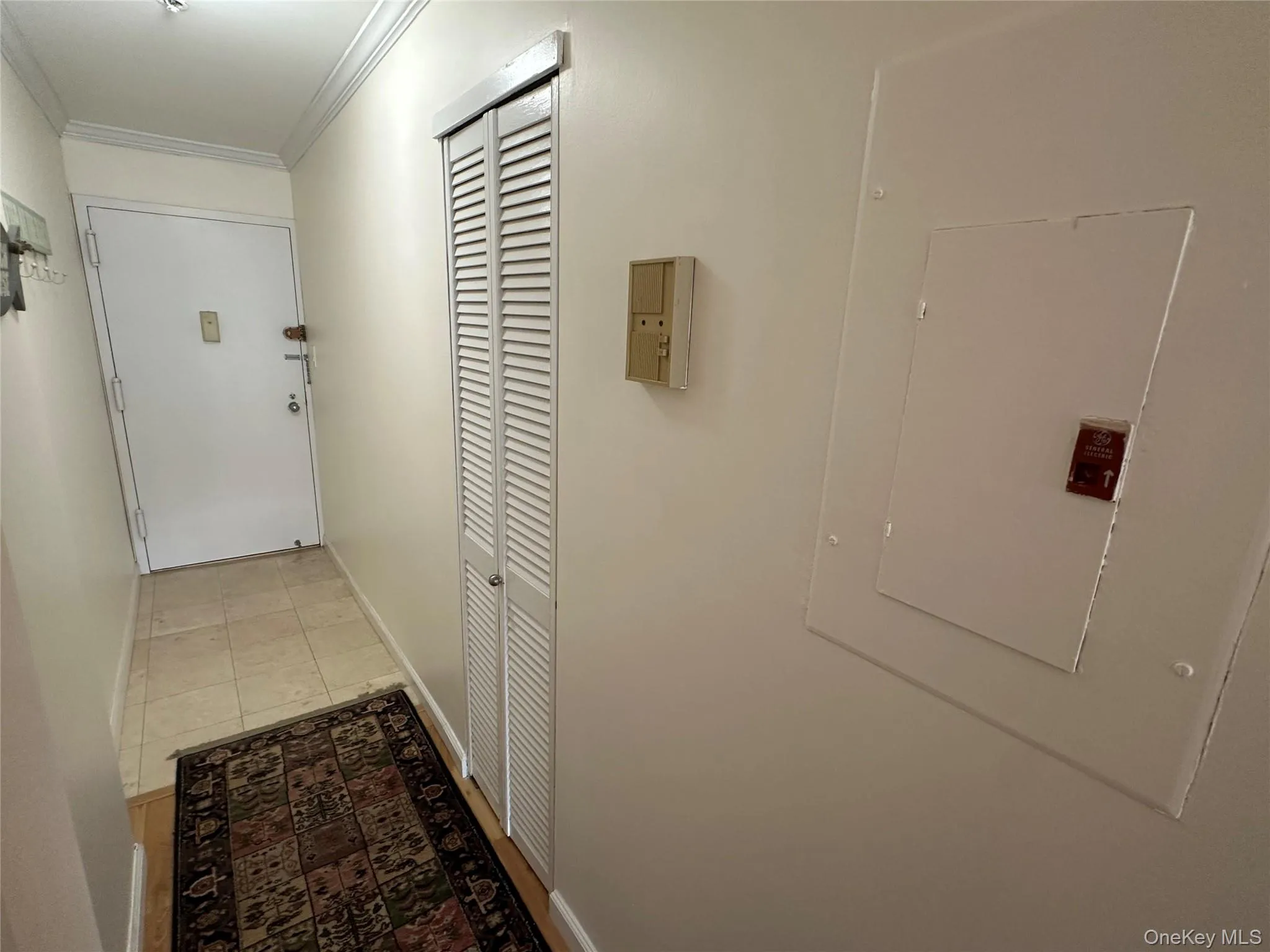 Hall featuring crown molding, electric panel, and light tile patterned flooring Hall featuring crown molding, electric panel, and light tile patterned flooring