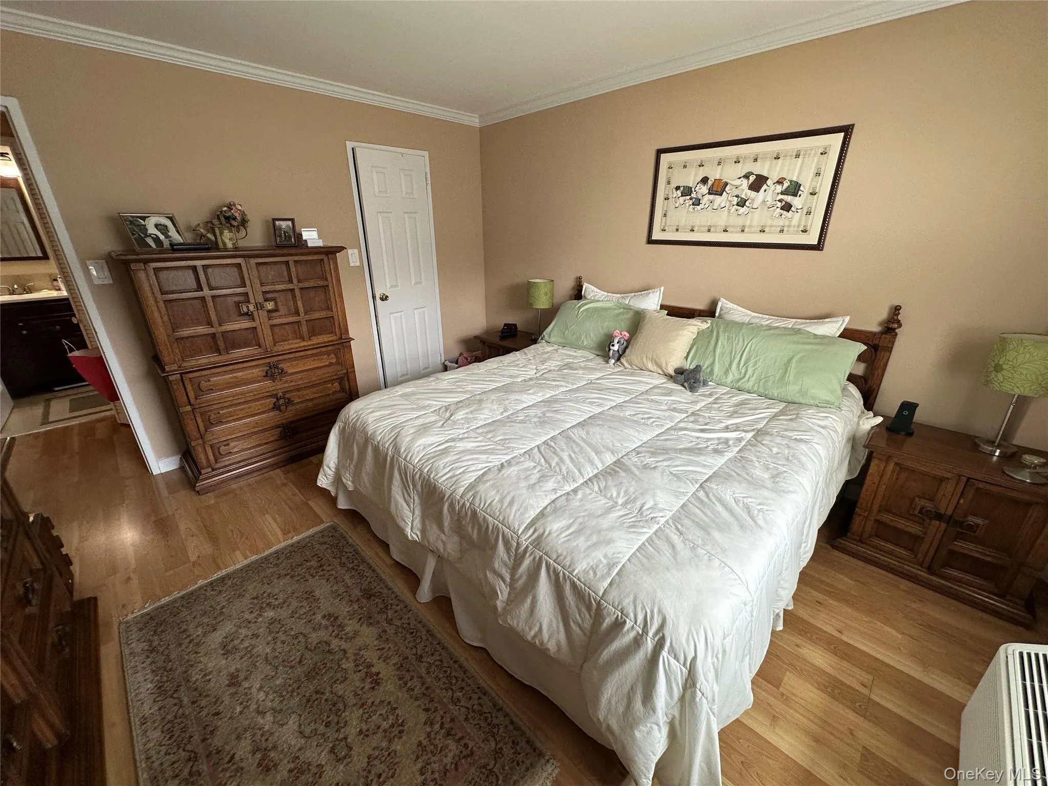 Bedroom featuring wood finished floors, ornamental molding, and connected bathroom Bedroom featuring wood finished floors, ornamental molding, and connected bathroom