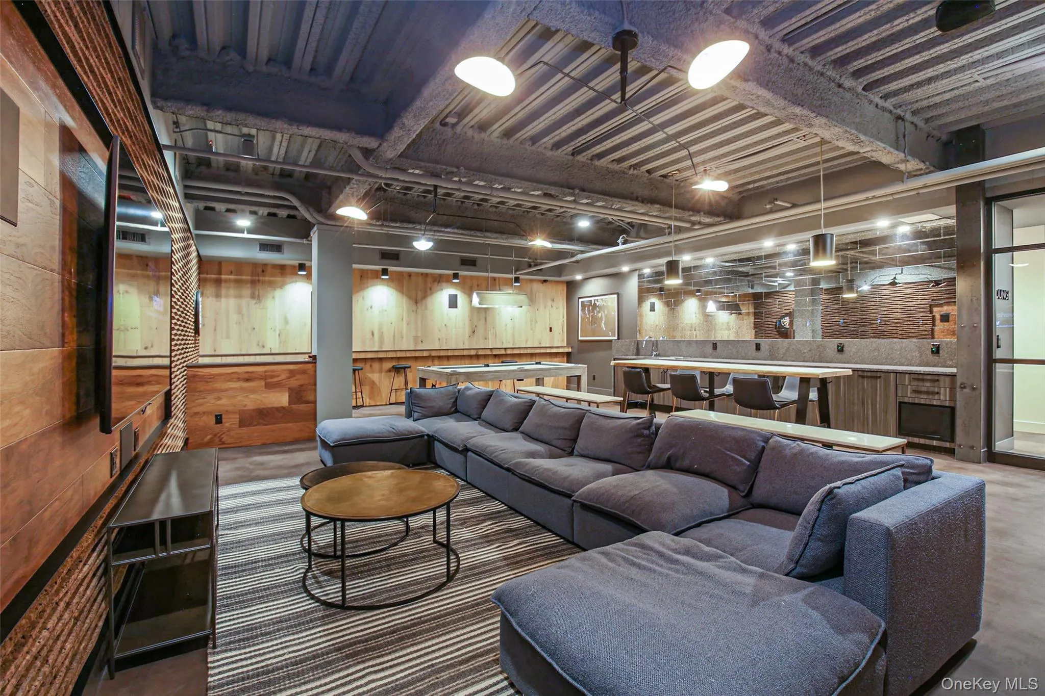 Living room with concrete flooring, rail lighting, bar, and wooden walls Living room with concrete flooring, rail lighting, bar, and wooden walls