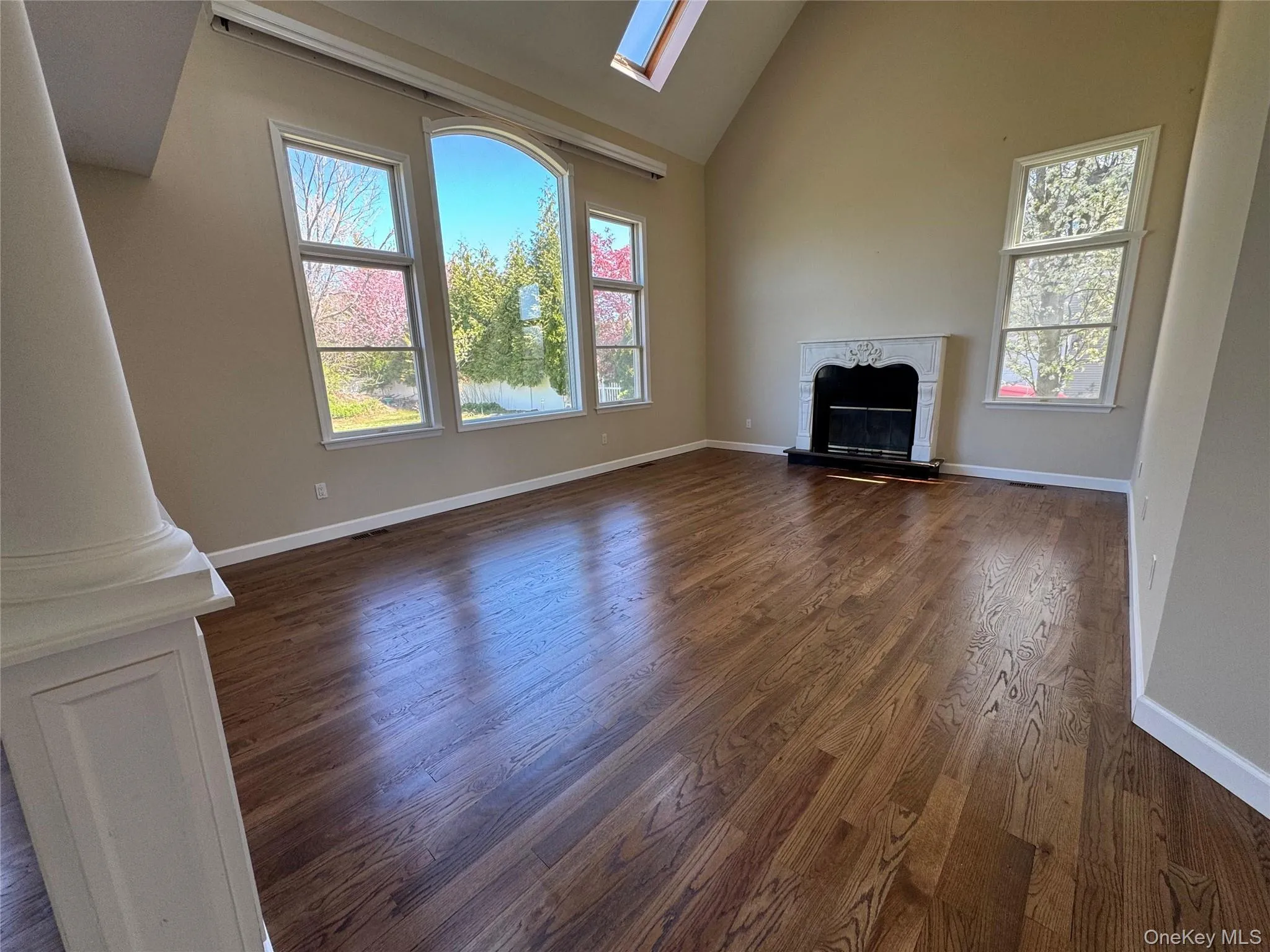 Spacious living area featuring high vaulted ceilings, skylights and a decorative fireplace with an ornate mantel Spacious living area featuring high vaulted ceilings, skylights and a decorative fireplace with an ornate mantel