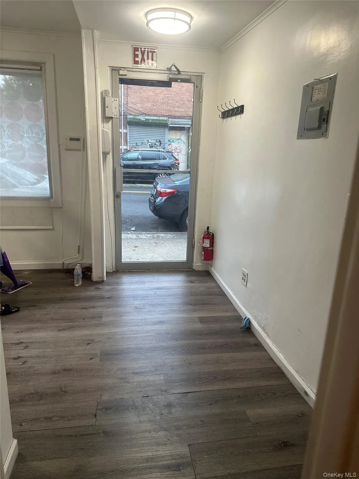 Doorway to outside with wood finished floors, crown molding, and electric panel Doorway to outside with wood finished floors, crown molding, and electric panel