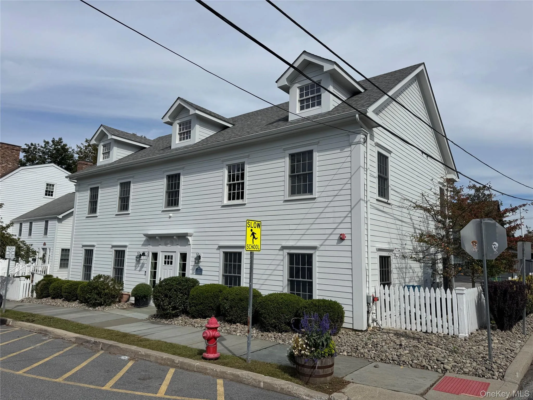 Colonial inspired home featuring a shingled roof and uncovered parking Colonial inspired home featuring a shingled roof and uncovered parking