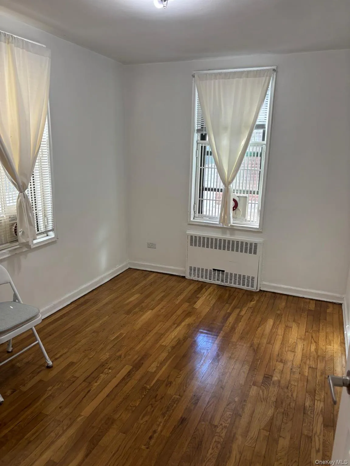 Unfurnished room featuring dark wood-style flooring and radiator Unfurnished room featuring dark wood-style flooring and radiator