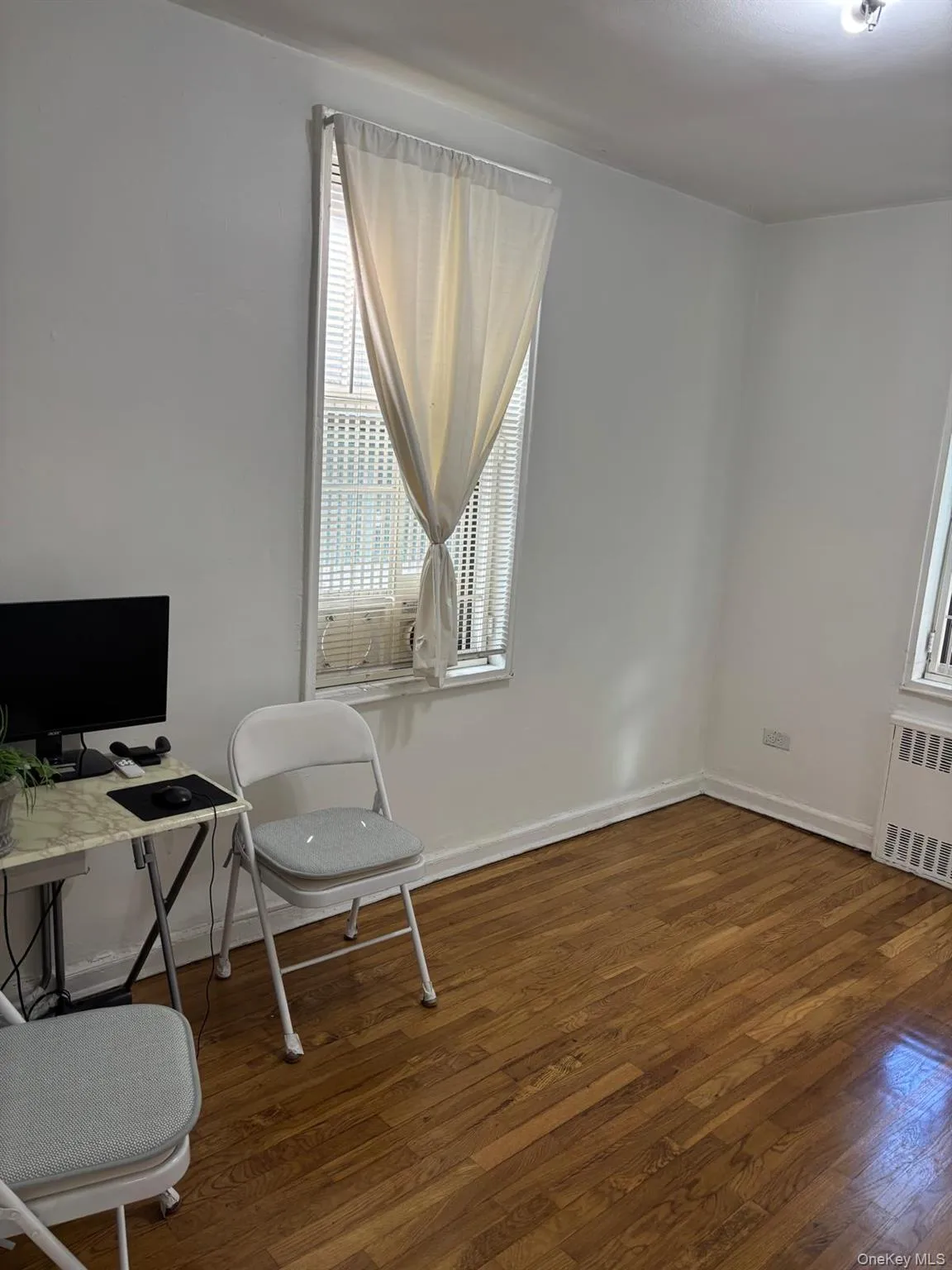 Office space featuring plenty of natural light, radiator, and dark wood-type flooring Office space featuring plenty of natural light, radiator, and dark wood-type flooring