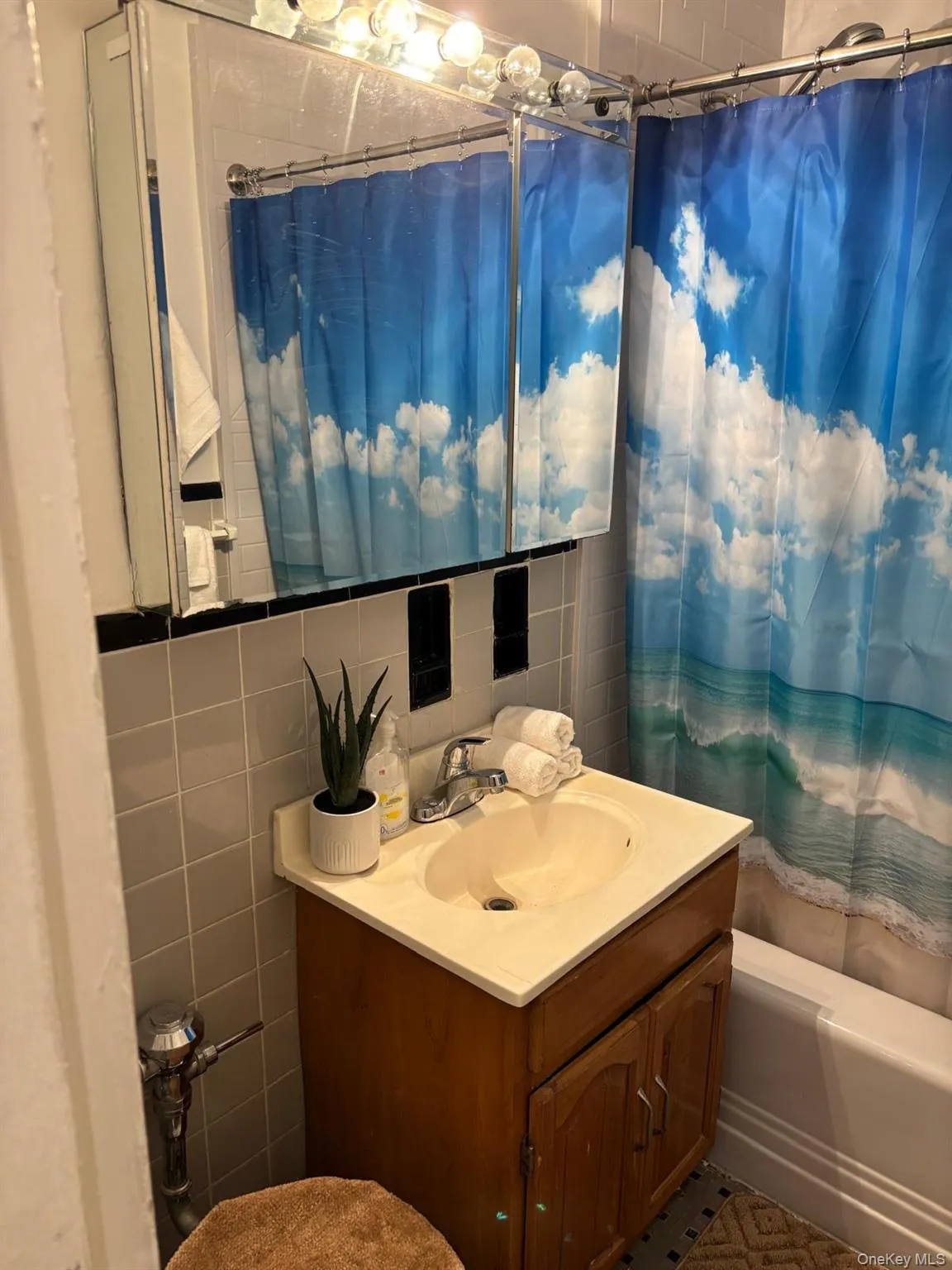 Full bathroom with tile walls, vanity, tasteful backsplash, and shower / bathtub combination with curtain Full bathroom with tile walls, vanity, tasteful backsplash, and shower / bathtub combination with curtain
