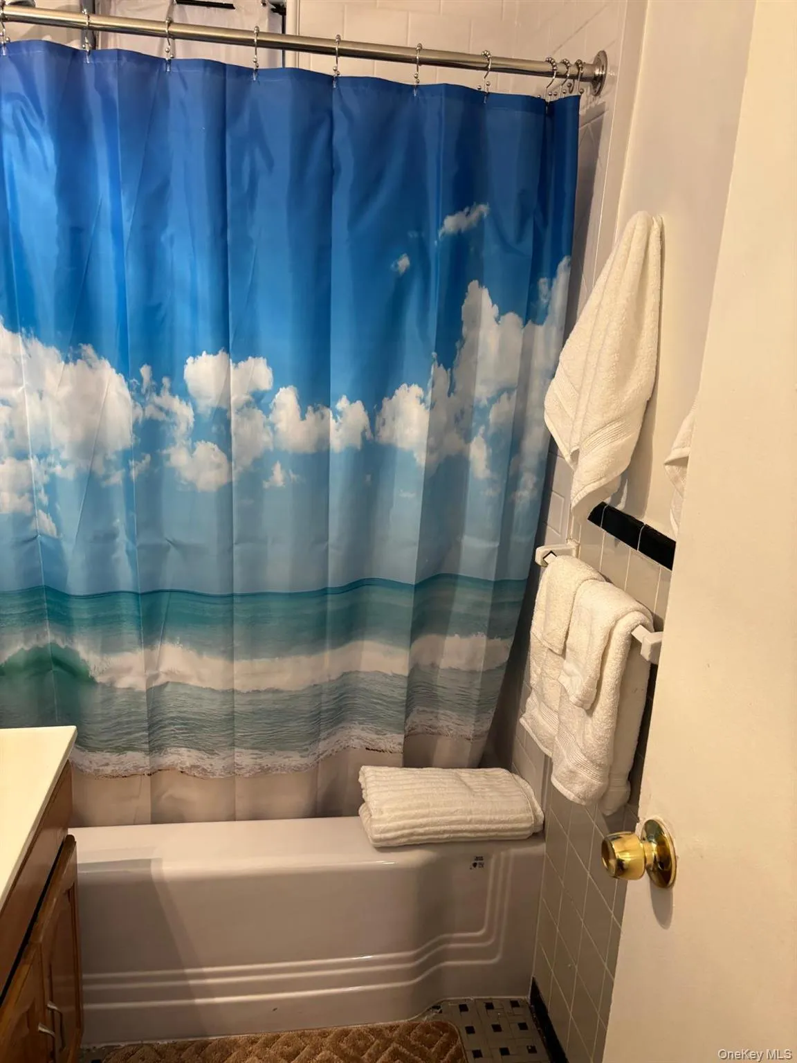 Full bathroom with vanity, shower / tub combo with curtain, and tile walls Full bathroom with vanity, shower / tub combo with curtain, and tile walls