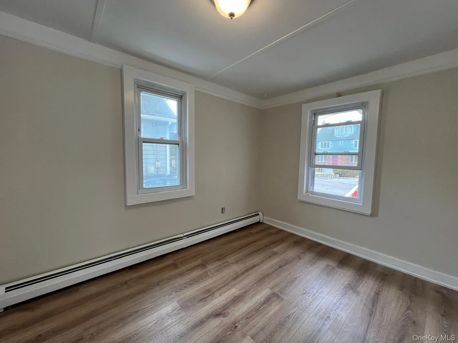 Unfurnished room featuring baseboard heating and wood finished floors Unfurnished room featuring baseboard heating and wood finished floors