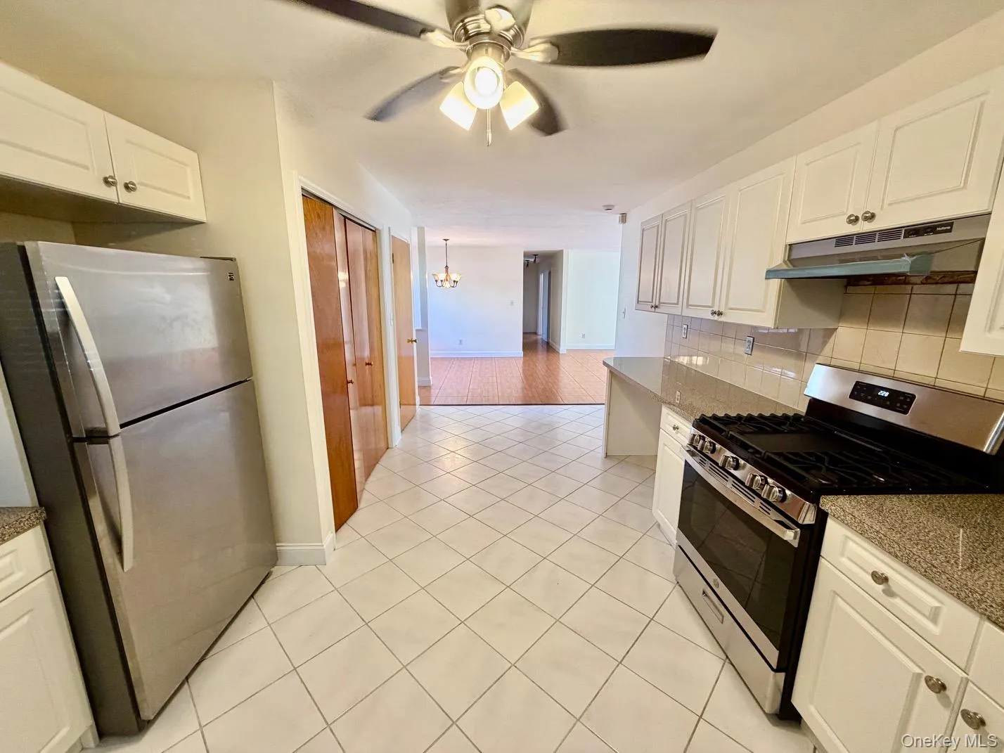 Kitchen featuring stainless steel appliances, white cabinetry, and dark stone countertops Kitchen featuring stainless steel appliances, white cabinetry, and dark stone countertops