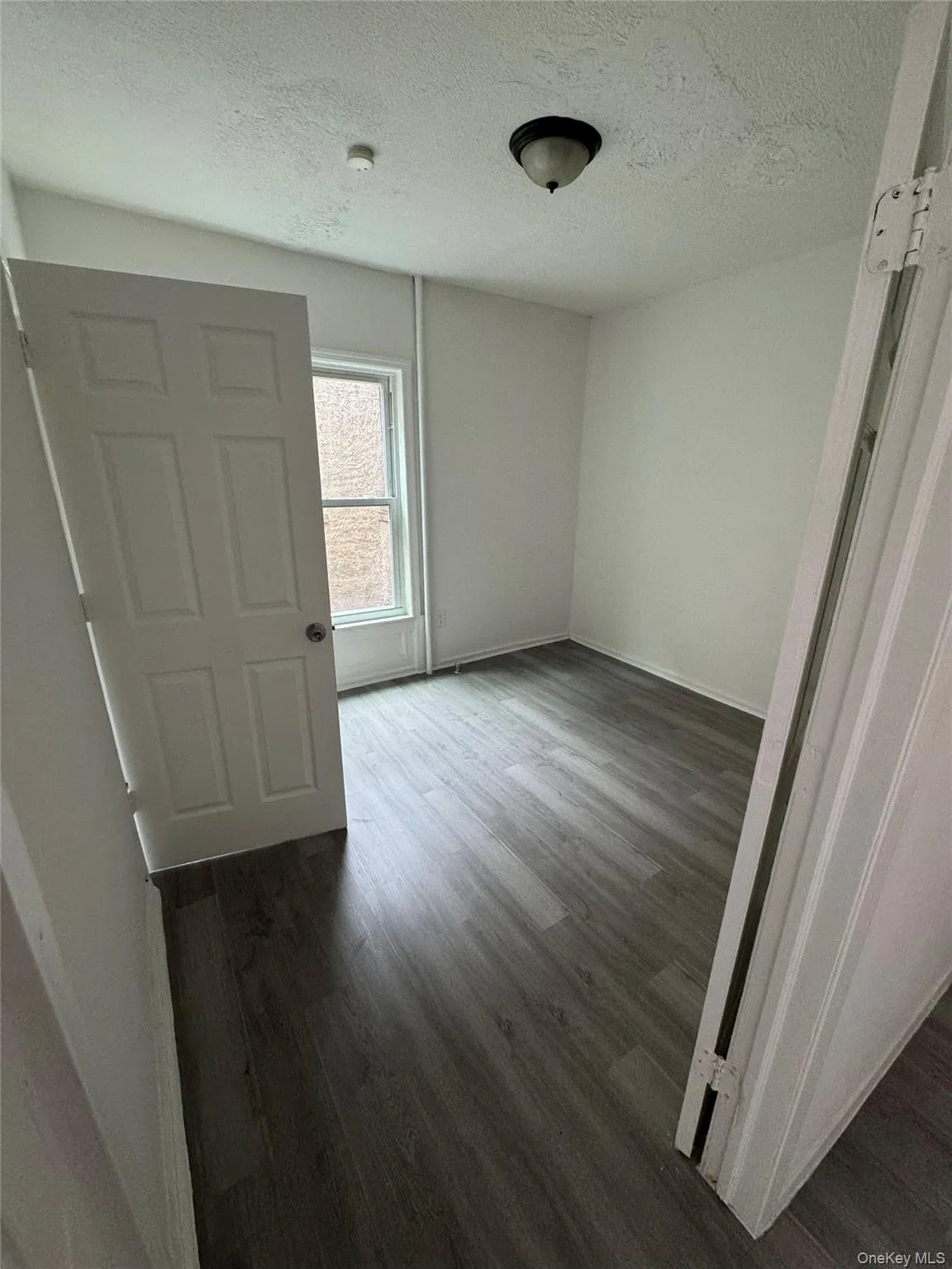 Empty room featuring a textured ceiling and dark wood-type flooring Empty room featuring a textured ceiling and dark wood-type flooring