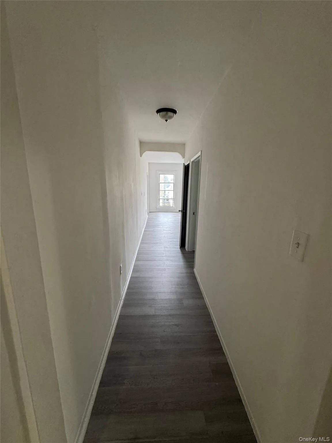 Corridor featuring dark wood-type flooring and baseboards Corridor featuring dark wood-type flooring and baseboards