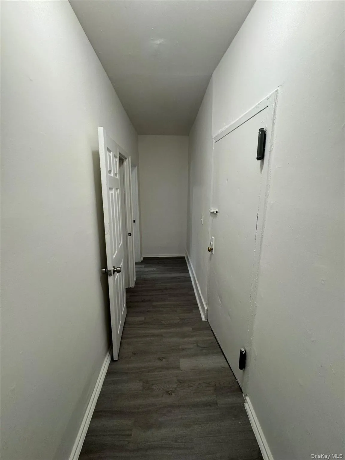Hallway featuring baseboards and dark wood finished floors Hallway featuring baseboards and dark wood finished floors