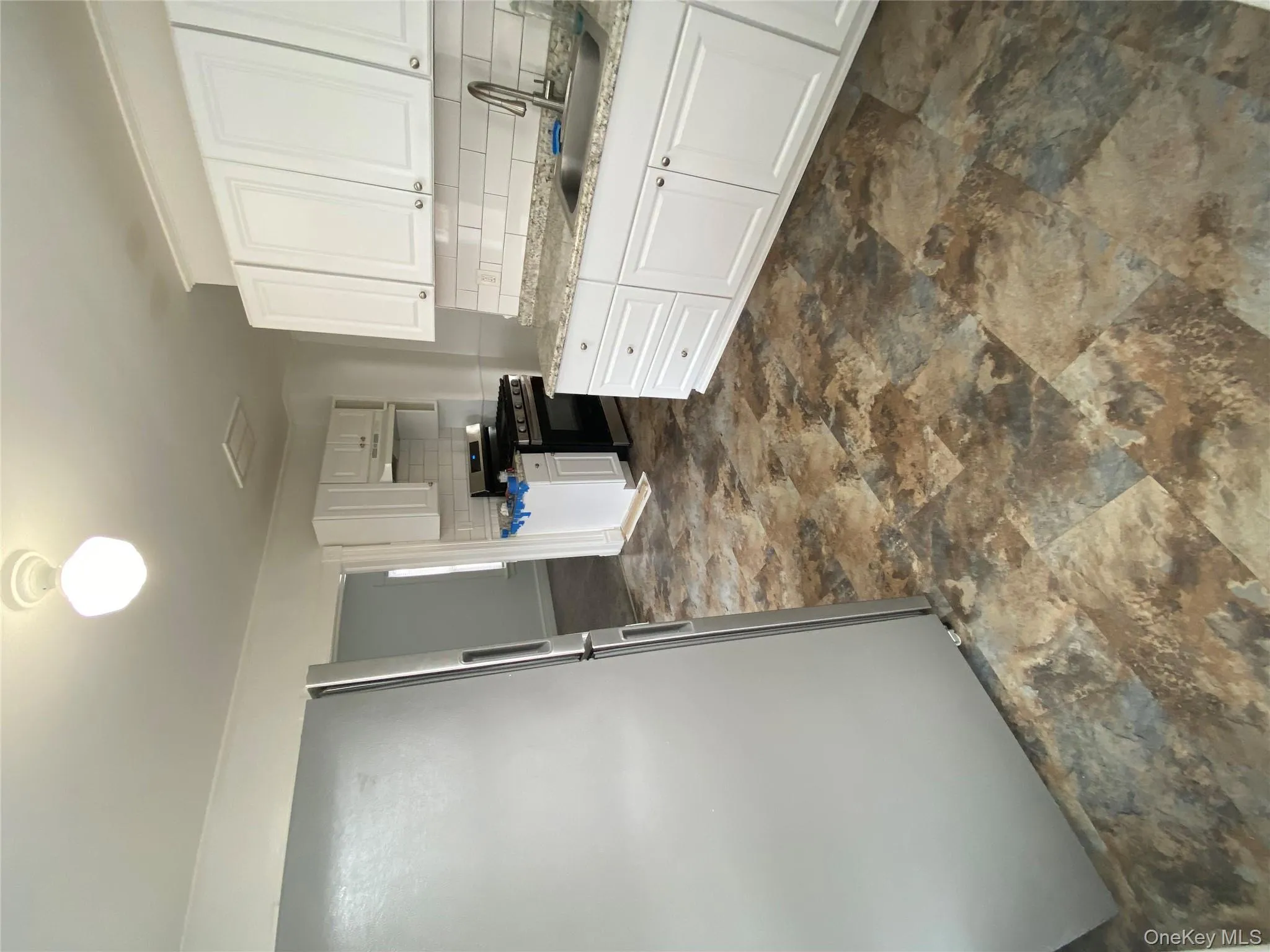 Kitchen with refrigerator, white cabinetry, tasteful backsplash, stove, and extractor fan Kitchen with refrigerator, white cabinetry, tasteful backsplash, stove, and extractor fan