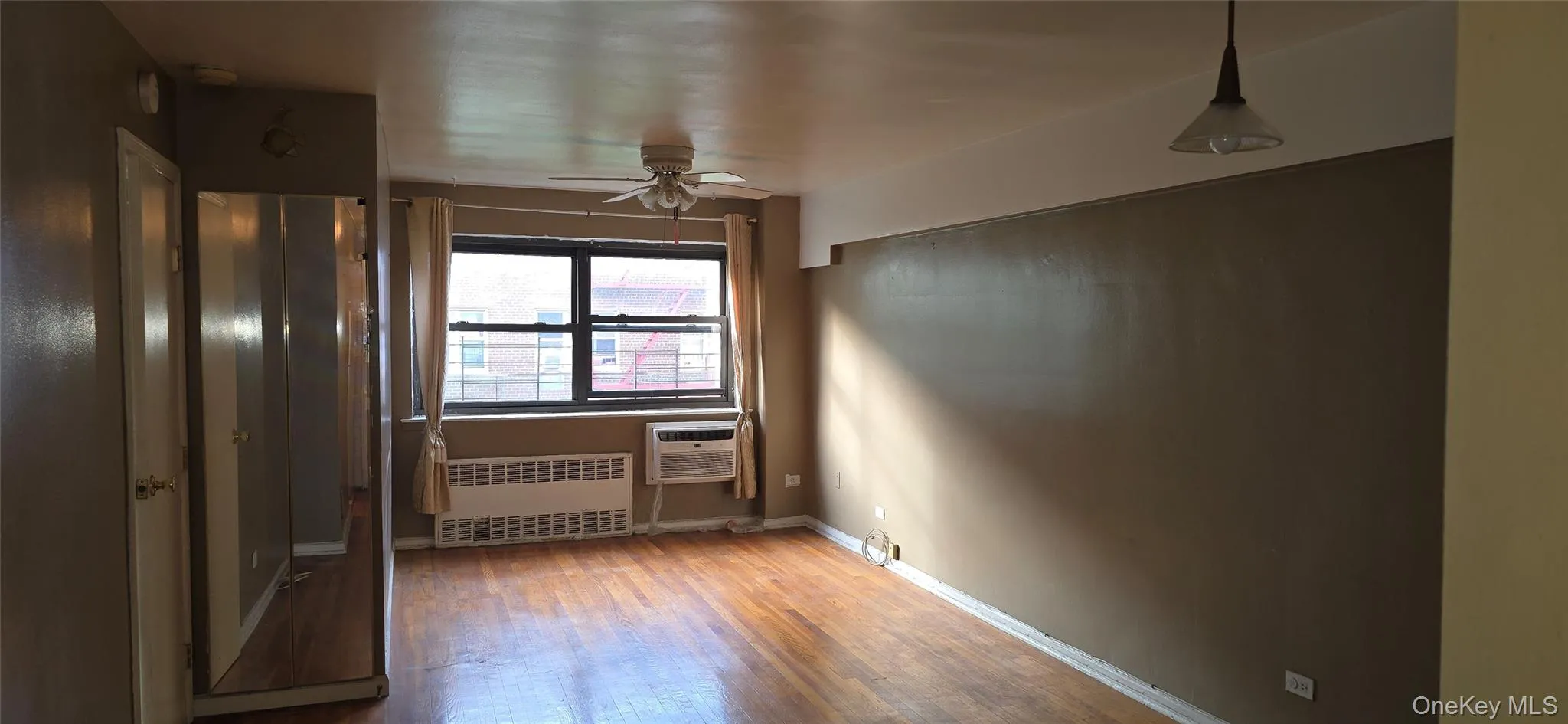 Unfurnished Living Room featuring wood finished floors, radiator, and a ceiling fan Unfurnished Living Room featuring wood finished floors, radiator, and a ceiling fan