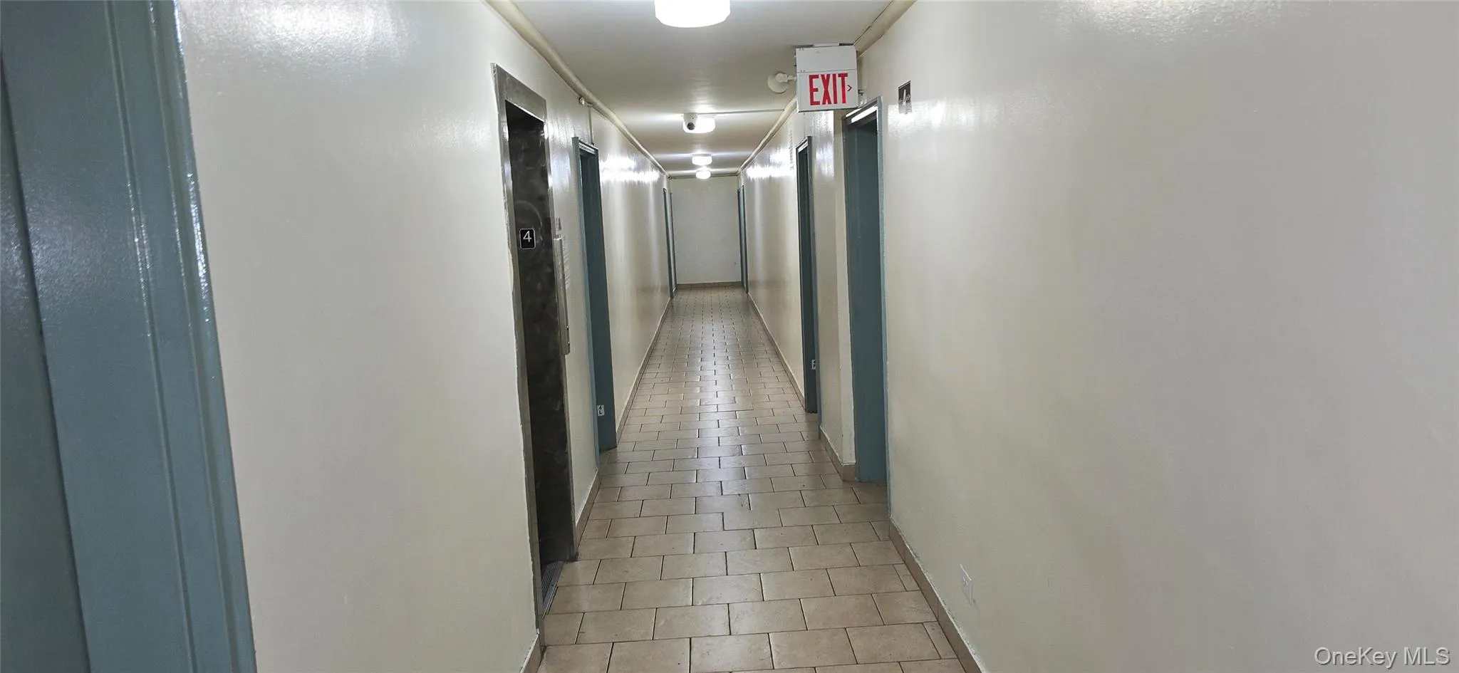 Hall with light tile patterned floors and baseboards Hall with light tile patterned floors and baseboards