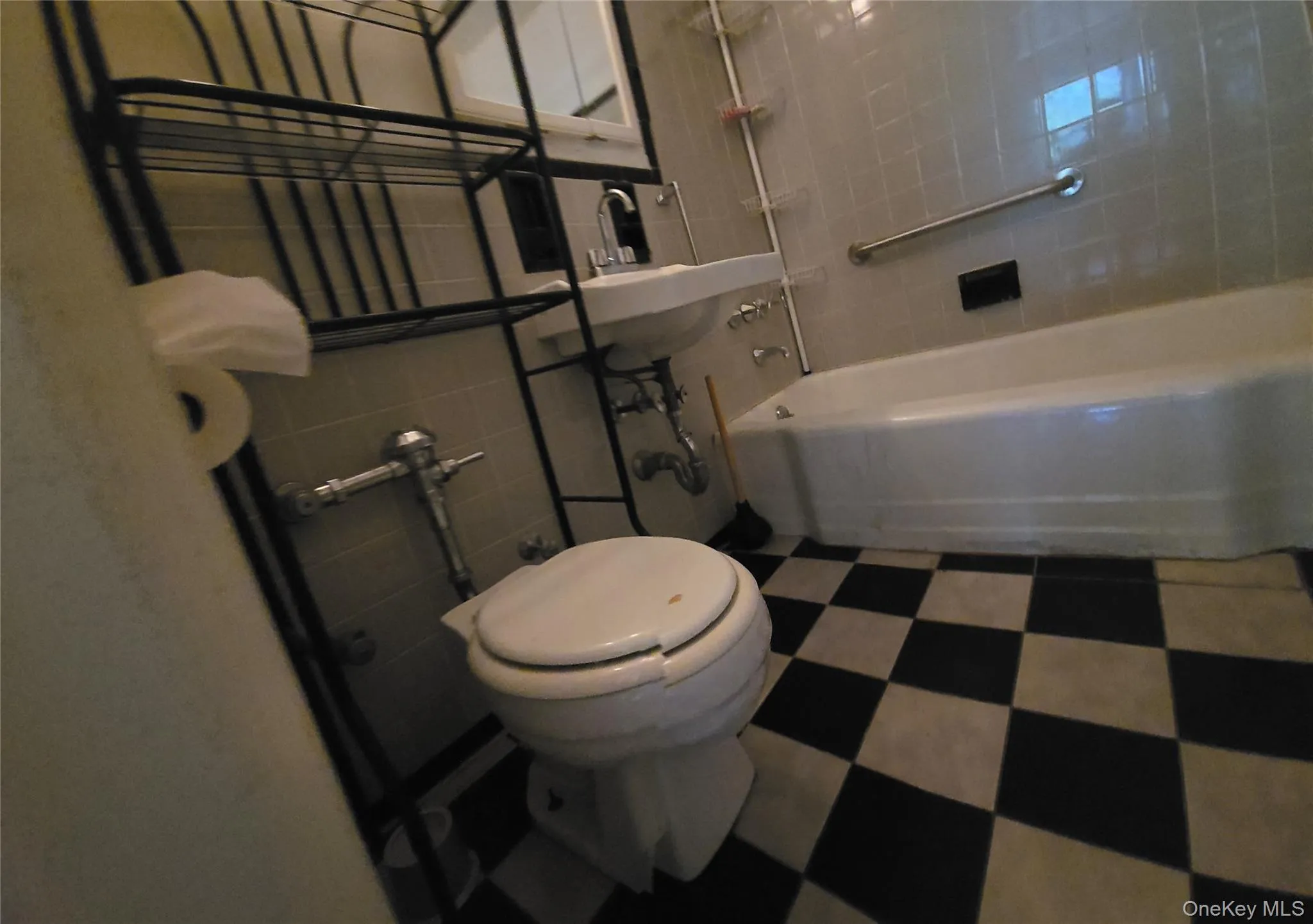 Full bath featuring shower / tub combination, tile walls, and dark floors Full bath featuring shower / tub combination, tile walls, and dark floors