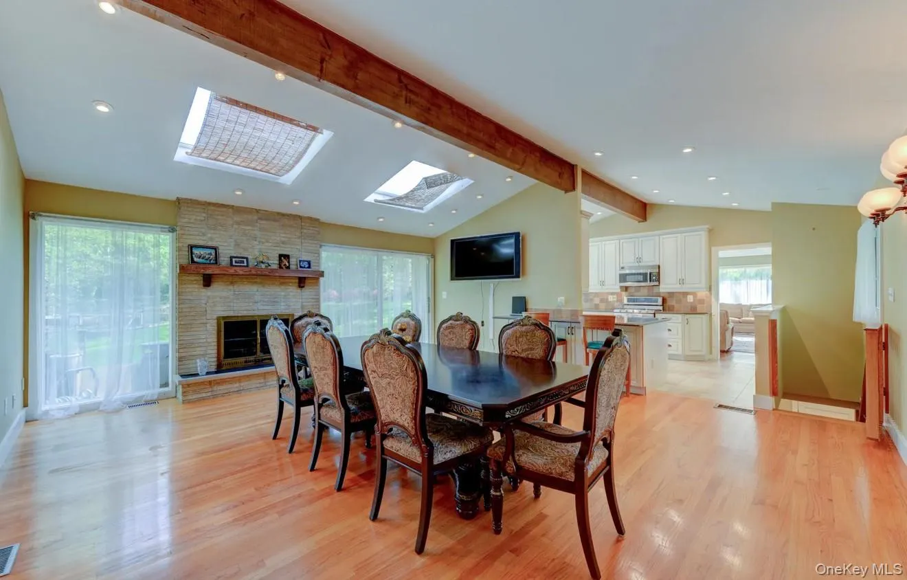 Dining space featuring a skylight, a fireplace, light wood finished floors, and recessed lighting Dining space featuring a skylight, a fireplace, light wood finished floors, and recessed lighting