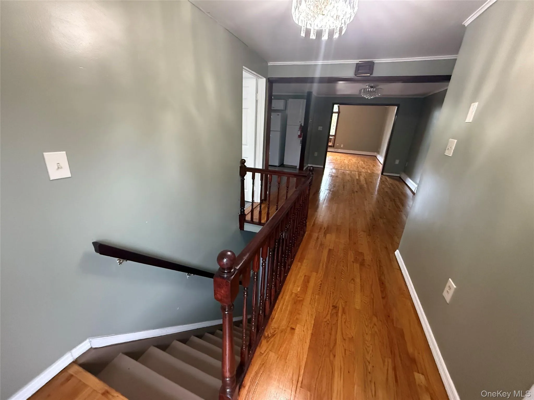 Hall with wood finished floors, a chandelier, and baseboard heating Hall with wood finished floors, a chandelier, and baseboard heating