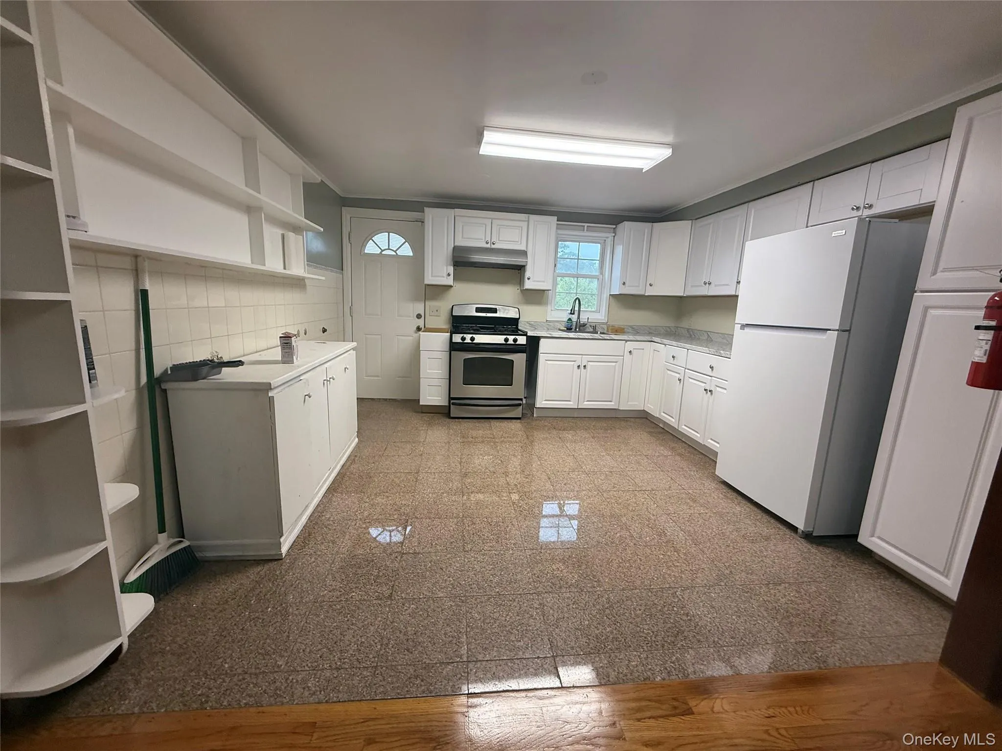 Kitchen featuring open shelves, white cabinets, light countertops, freestanding refrigerator, and gas range Kitchen featuring open shelves, white cabinets, light countertops, freestanding refrigerator, and gas range
