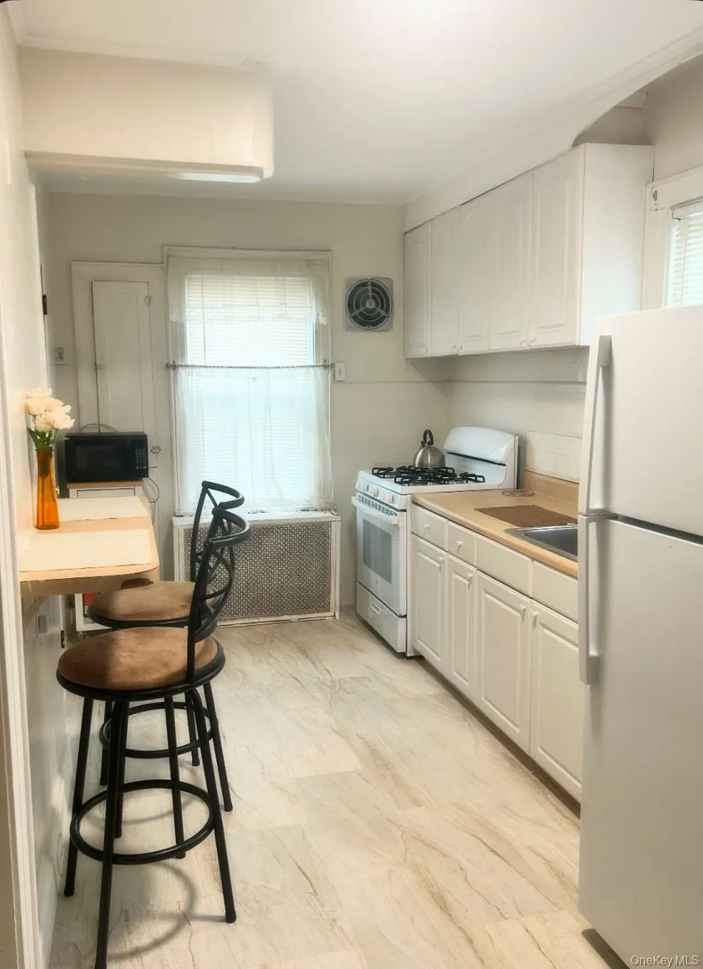 Kitchen featuring white appliances, white cabinetry, and light countertops Kitchen featuring white appliances, white cabinetry, and light countertops
