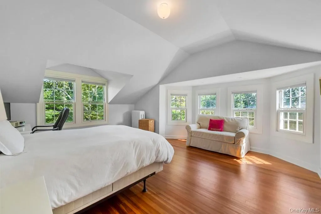 Bedroom featuring lofted ceiling, wood finished floors, and radiator Bedroom featuring lofted ceiling, wood finished floors, and radiator