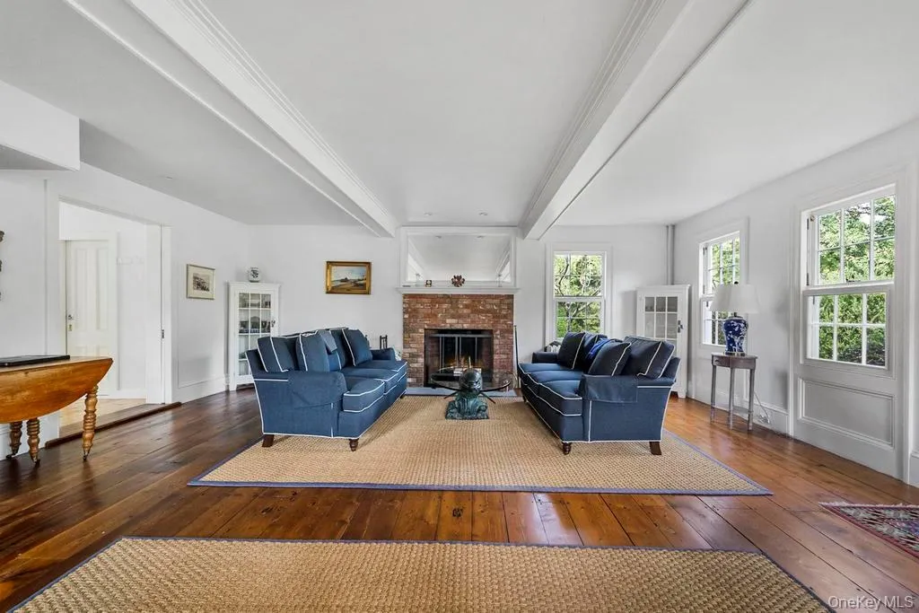 Living room with dark wood-style floors, beamed ceiling, a fireplace, and ornamental molding Living room with dark wood-style floors, beamed ceiling, a fireplace, and ornamental molding