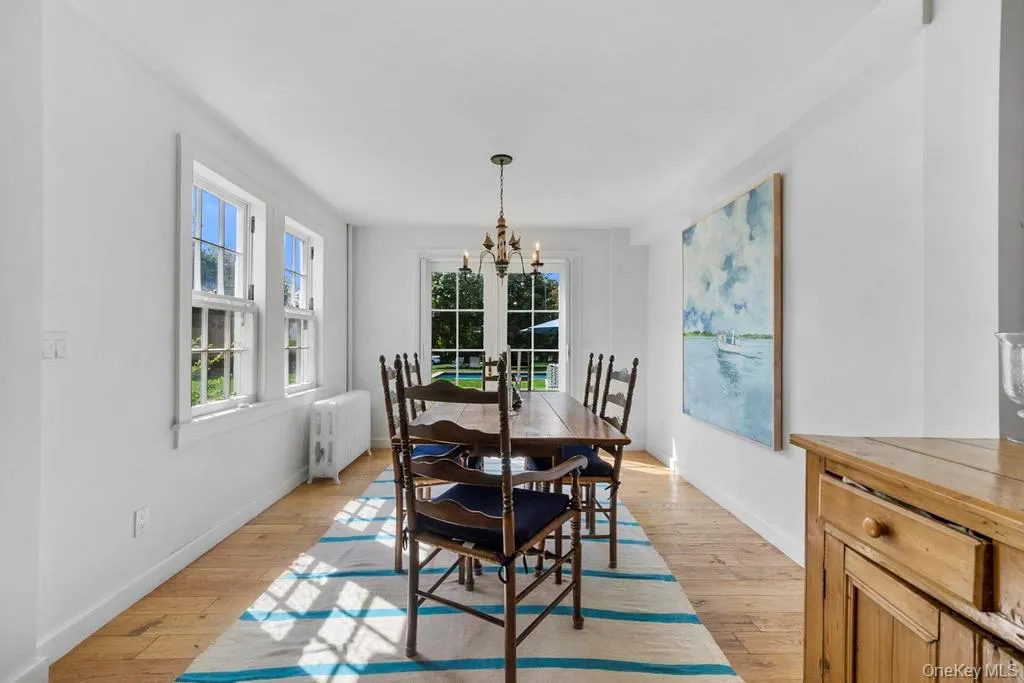 Dining area featuring radiator, light wood-style flooring, plenty of natural light, and a chandelier Dining area featuring radiator, light wood-style flooring, plenty of natural light, and a chandelier