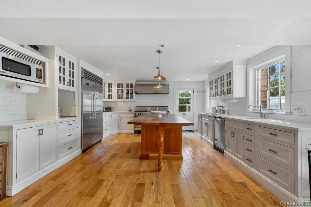 Kitchen with white cabinetry, backsplash, glass insert cabinets, and recessed lighting Kitchen with white cabinetry, backsplash, glass insert cabinets, and recessed lighting