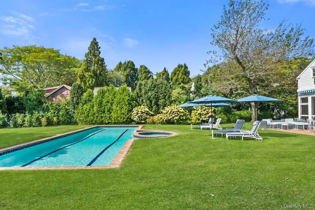 View of swimming pool featuring a lawn, a patio, a pool with connected hot tub, and view of wooded area View of swimming pool featuring a lawn, a patio, a pool with connected hot tub, and view of wooded area