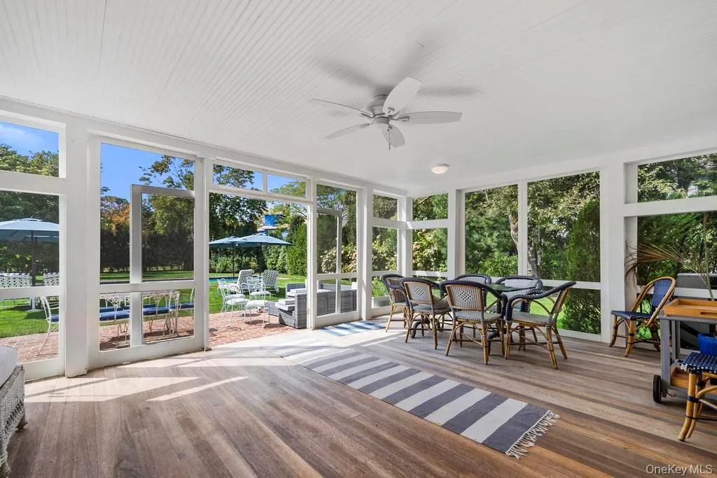 Sunroom / solarium featuring outdoor dining space, floor to ceiling windows, a ceiling fan, and wood finished floors Sunroom / solarium featuring outdoor dining space, floor to ceiling windows, a ceiling fan, and wood finished floors