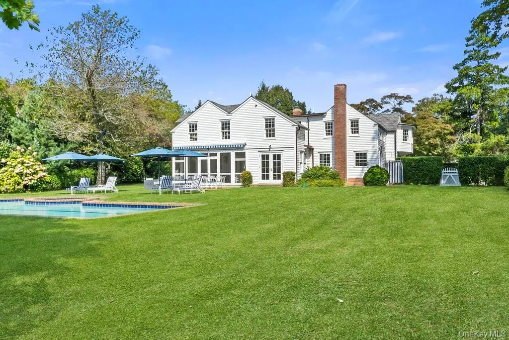 Back of house with a yard, a sunroom, a chimney, an outdoor pool, and a patio Back of house with a yard, a sunroom, a chimney, an outdoor pool, and a patio