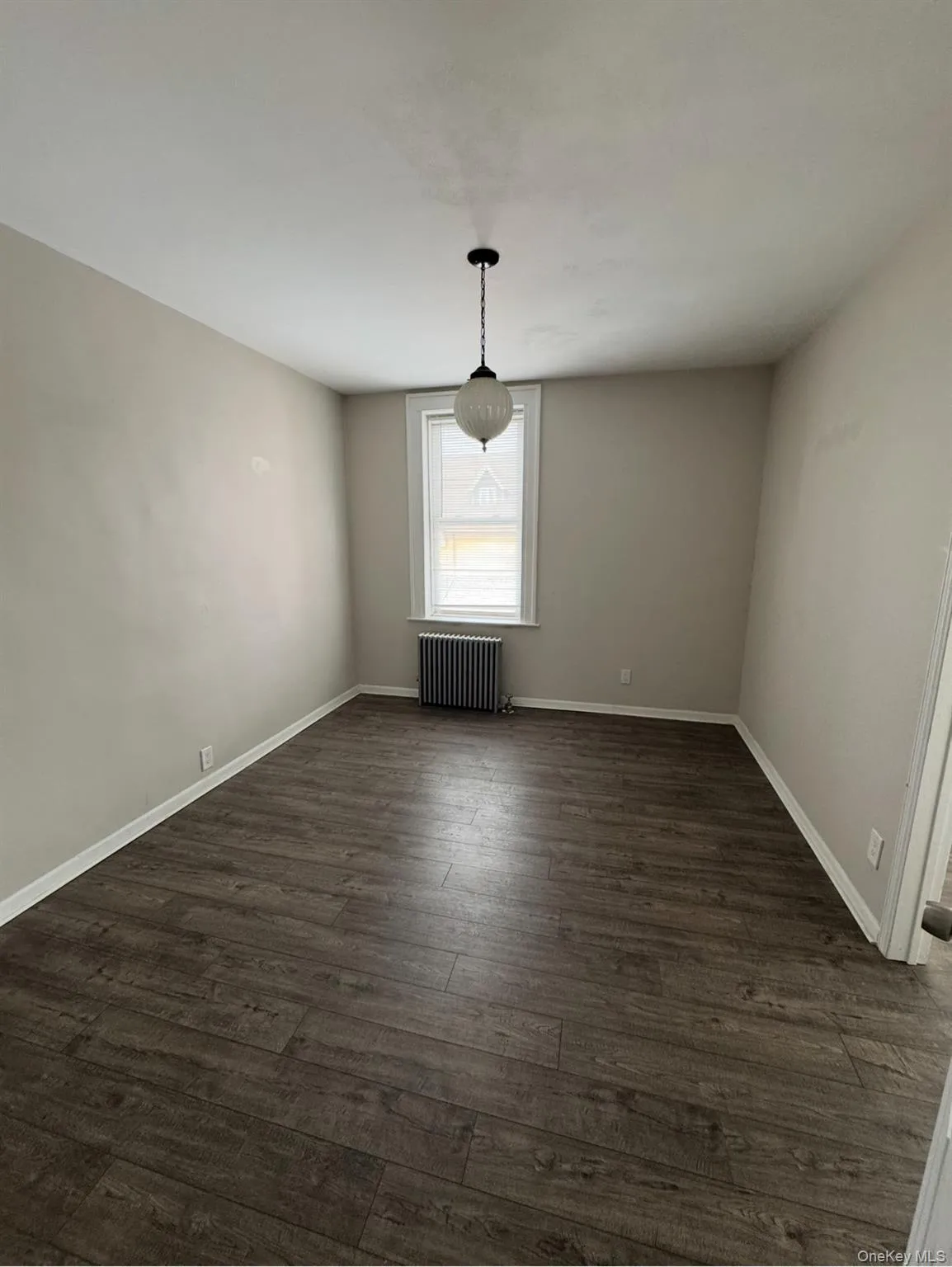 Unfurnished dining area featuring dark wood finished floors and radiator heating unit Unfurnished dining area featuring dark wood finished floors and radiator heating unit