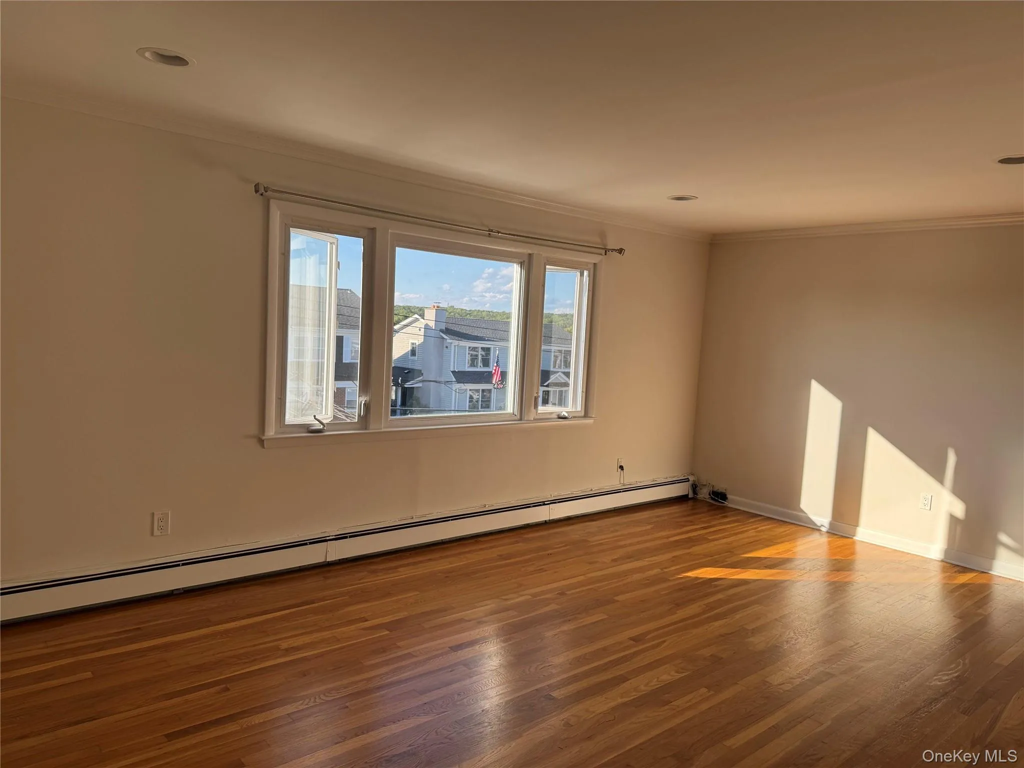 Empty room featuring a baseboard heating unit, wood finished floors, crown molding, and recessed lighting Empty room featuring a baseboard heating unit, wood finished floors, crown molding, and recessed lighting