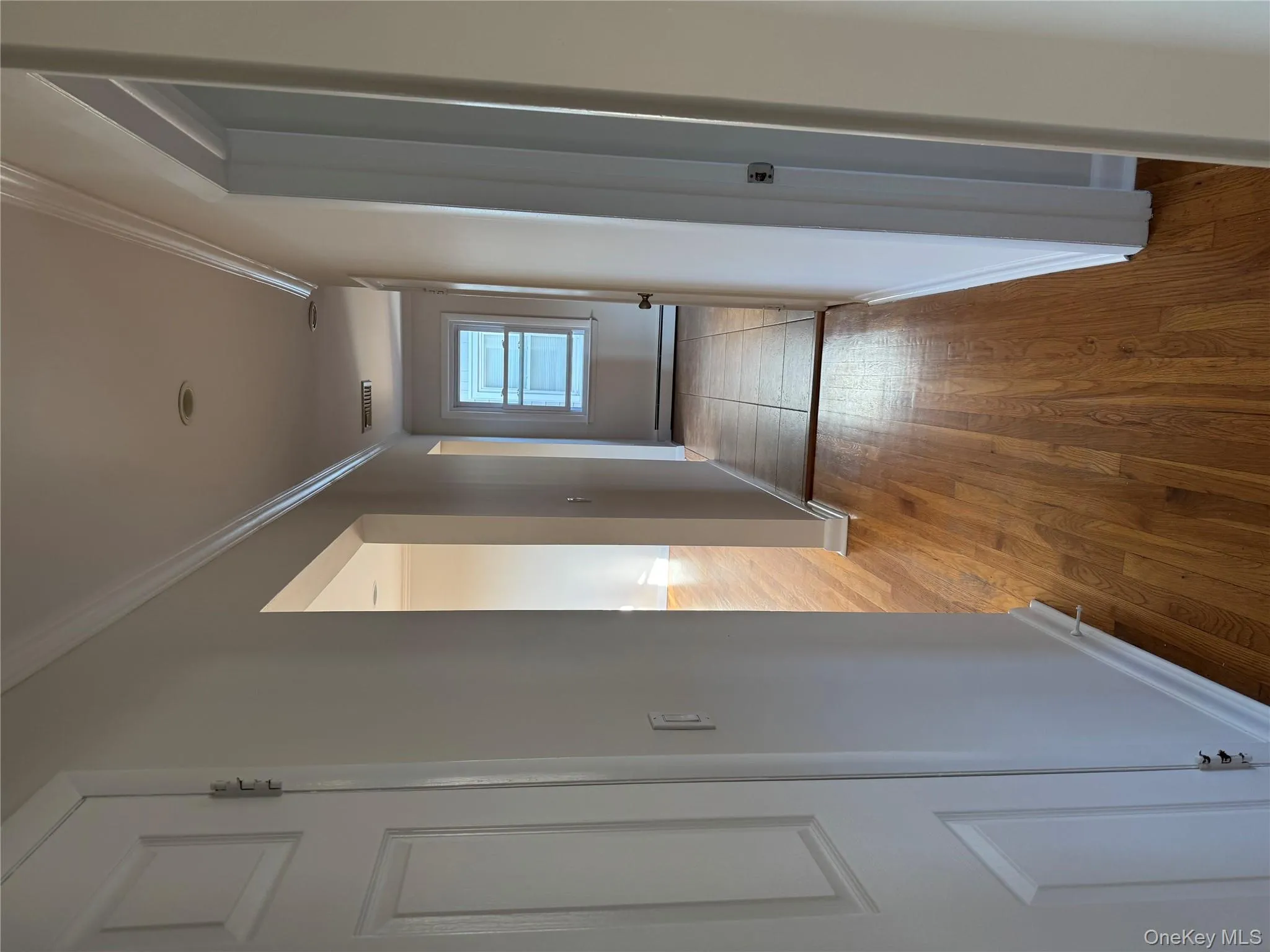 Corridor featuring wood finished floors, crown molding, and a baseboard radiator Corridor featuring wood finished floors, crown molding, and a baseboard radiator