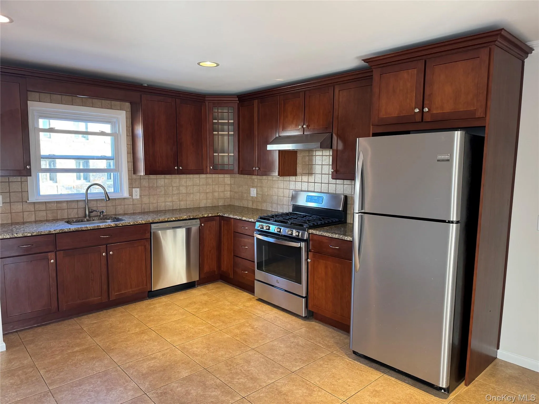 Kitchen with stainless steel appliances, light stone counters, glass insert cabinets, backsplash, and recessed lighting Kitchen with stainless steel appliances, light stone counters, glass insert cabinets, backsplash, and recessed lighting