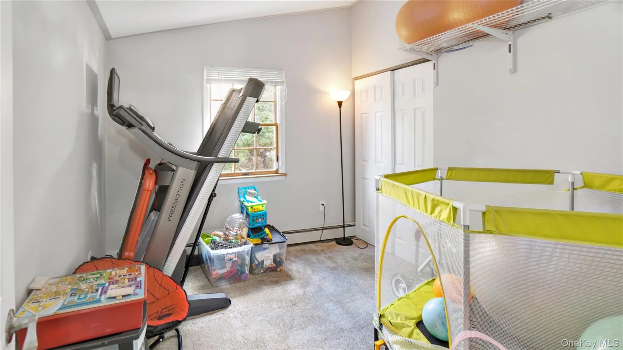 Bedroom with light carpet, baseboard heating, lofted ceiling, and a closet Bedroom with light carpet, baseboard heating, lofted ceiling, and a closet