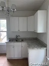 Kitchen featuring white cabinets, decorative light fixtures, a chandelier, light countertops, and dark tile patterned flooring Kitchen featuring white cabinets, decorative light fixtures, a chandelier, light countertops, and dark tile patterned flooring