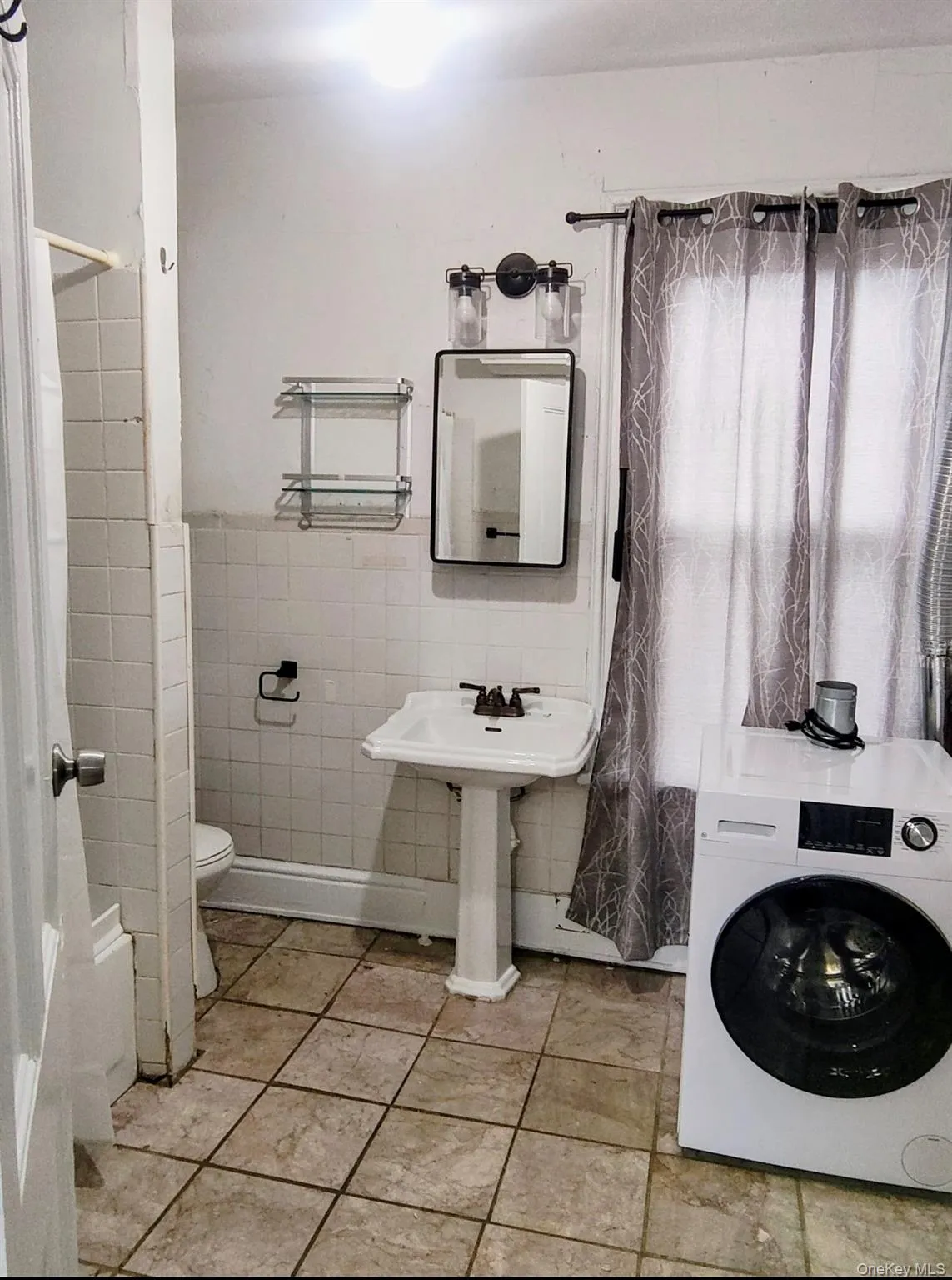 Bathroom with washer / dryer, tile walls, a wainscoted wall, and shower / tub combo with curtain Bathroom with washer / dryer, tile walls, a wainscoted wall, and shower / tub combo with curtain