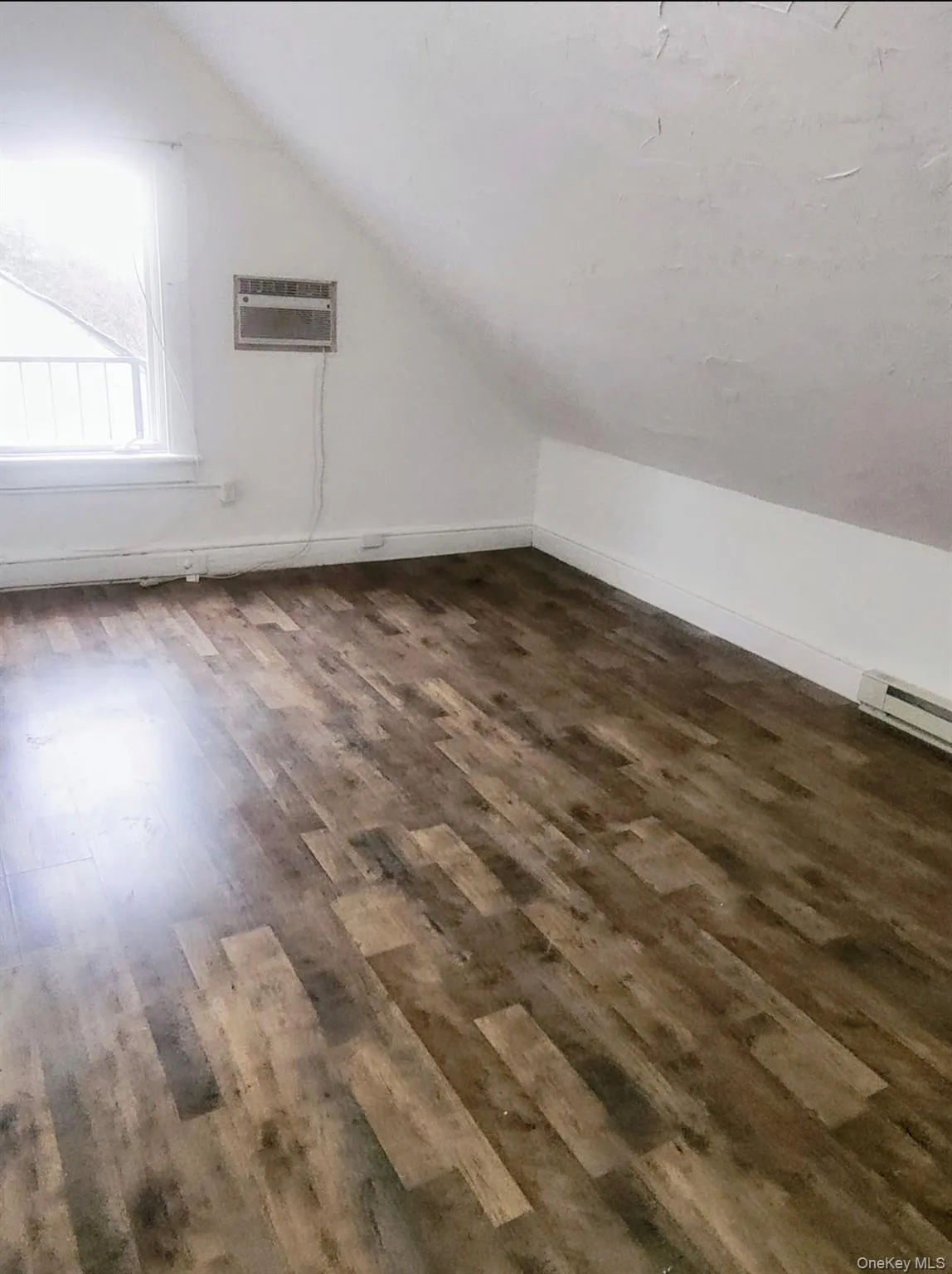 Bonus room featuring vaulted ceiling, dark wood-style flooring, and baseboard heating Bonus room featuring vaulted ceiling, dark wood-style flooring, and baseboard heating