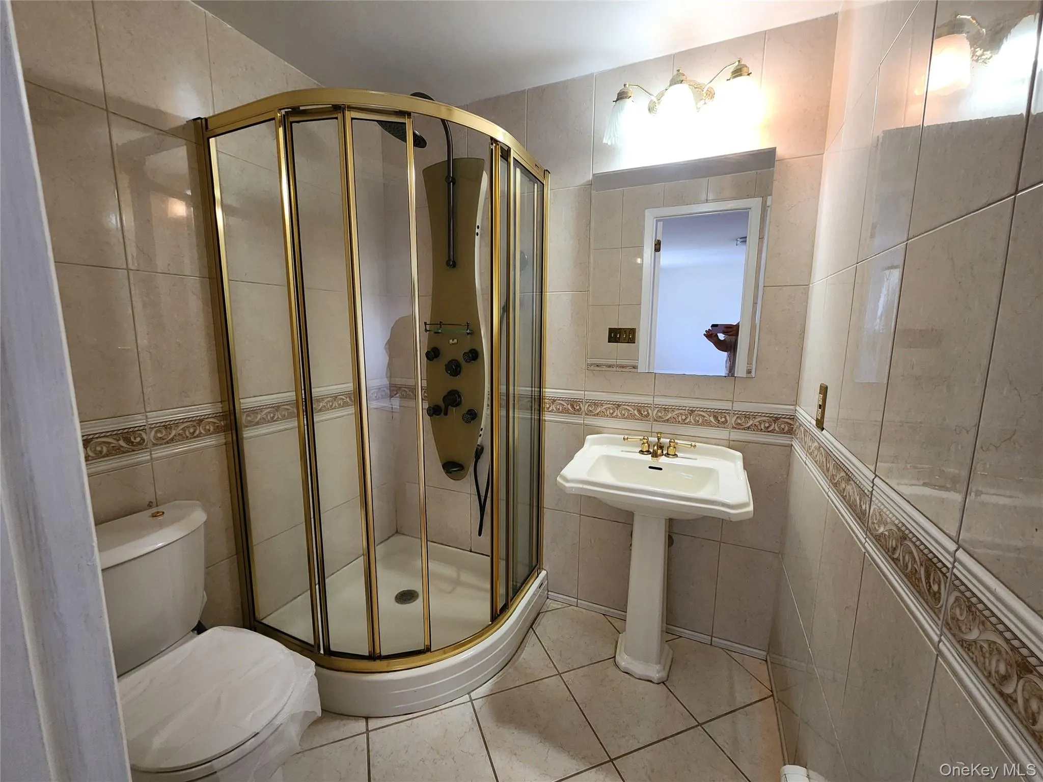 Full bath with tile walls, light tile patterned flooring, and a shower stall Full bath with tile walls, light tile patterned flooring, and a shower stall