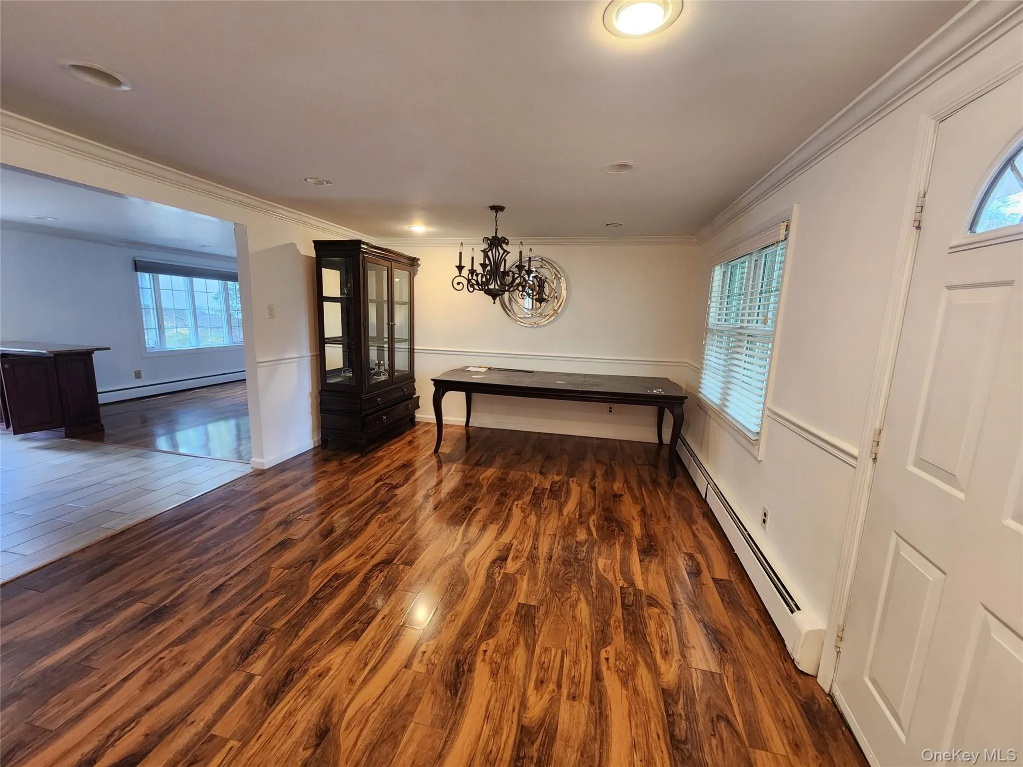 Unfurnished dining area with dark wood finished floors, baseboard heating, ornamental molding, and healthy amount of natural light Unfurnished dining area with dark wood finished floors, baseboard heating, ornamental molding, and healthy amount of natural light