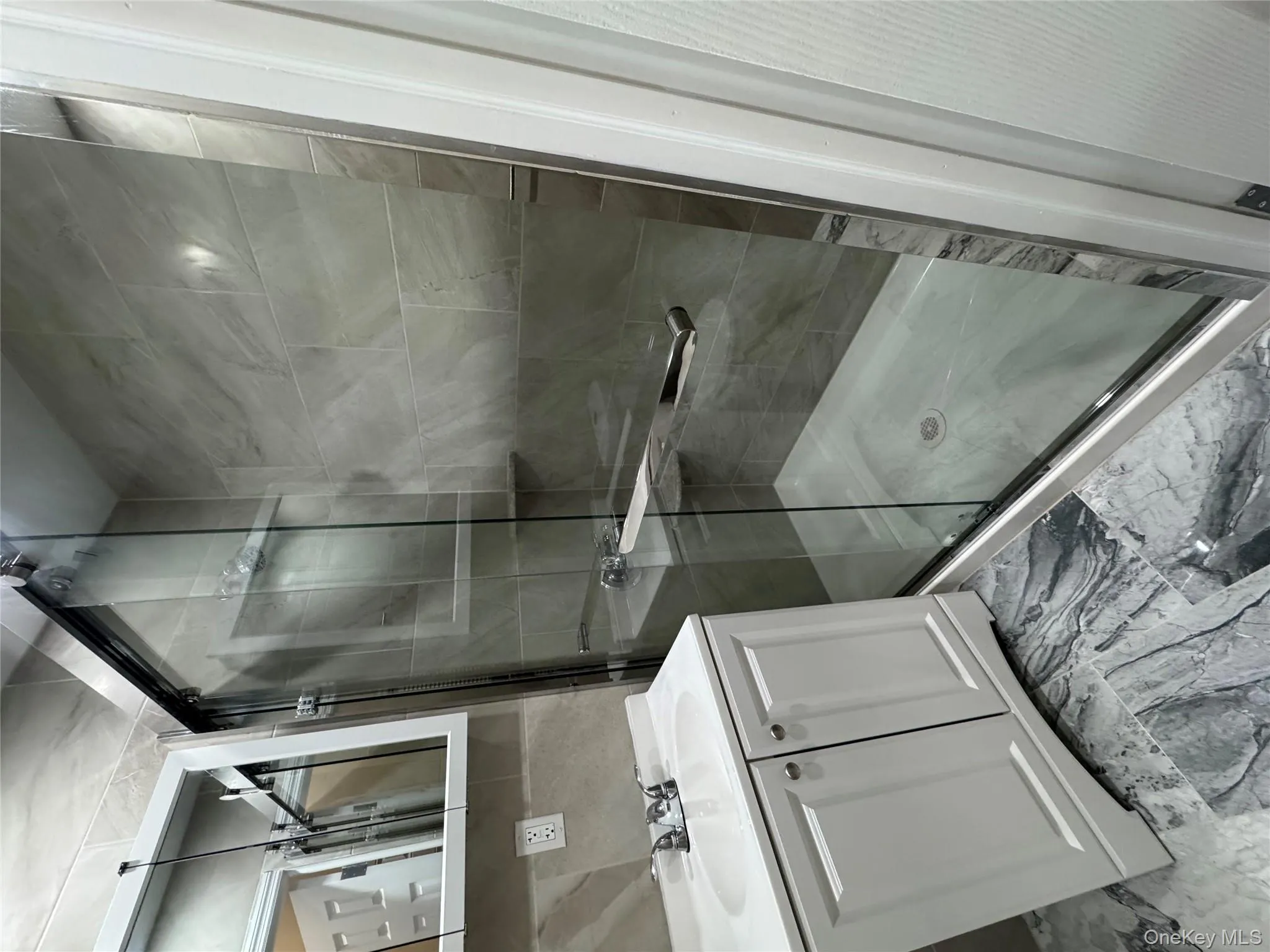 Full bathroom with a stall shower, vanity, and light marble finish flooring Full bathroom with a stall shower, vanity, and light marble finish flooring