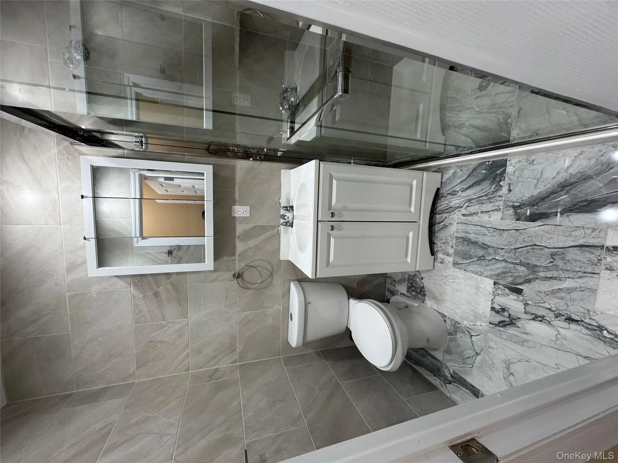 Full bath featuring tile walls, vanity, a shower stall, and light marble finish floors Full bath featuring tile walls, vanity, a shower stall, and light marble finish floors