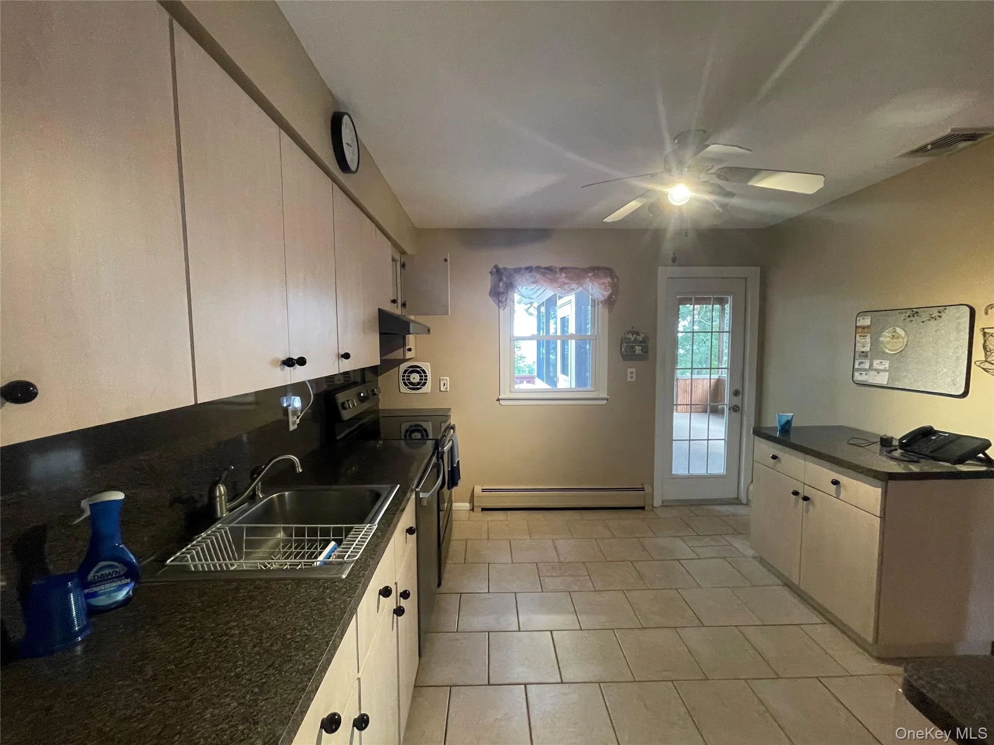 Kitchen with electric stove, baseboard heating, ceiling fan, light tile patterned flooring, and under cabinet range hood Kitchen with electric stove, baseboard heating, ceiling fan, light tile patterned flooring, and under cabinet range hood