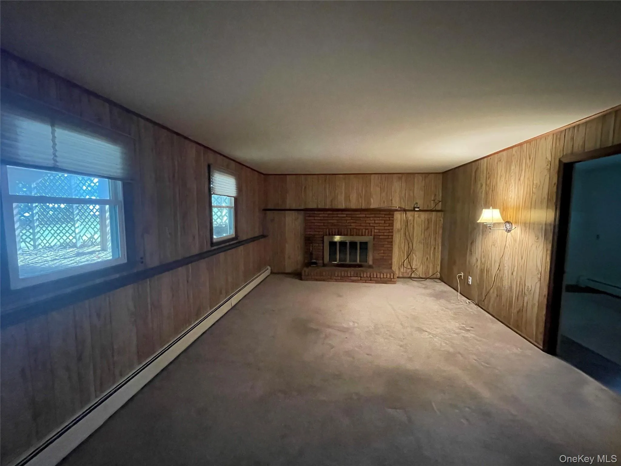 Unfurnished living room featuring a baseboard radiator, wood walls, and a fireplace Unfurnished living room featuring a baseboard radiator, wood walls, and a fireplace