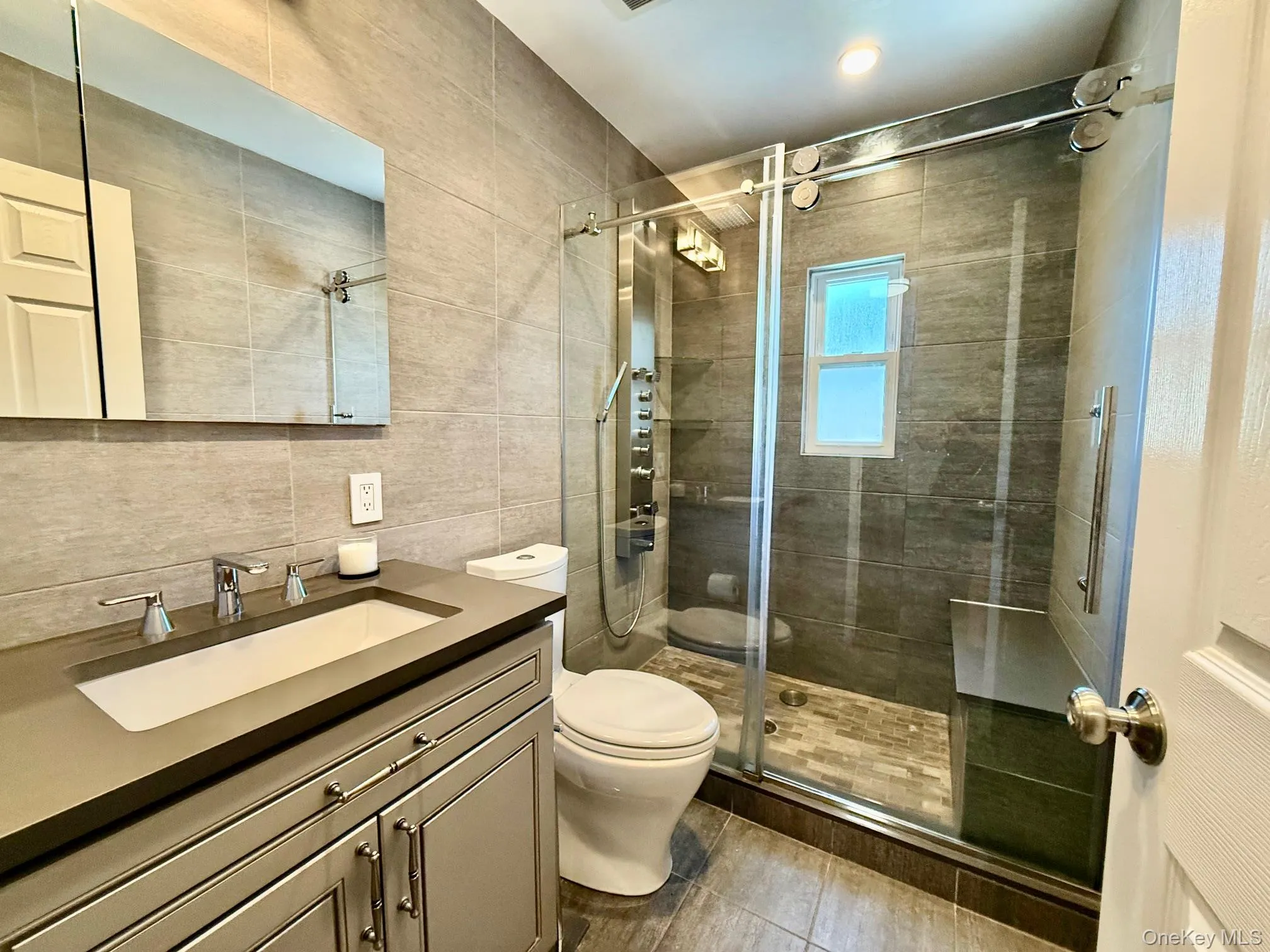 Bathroom featuring tile walls, vanity, and a stall shower Bathroom featuring tile walls, vanity, and a stall shower