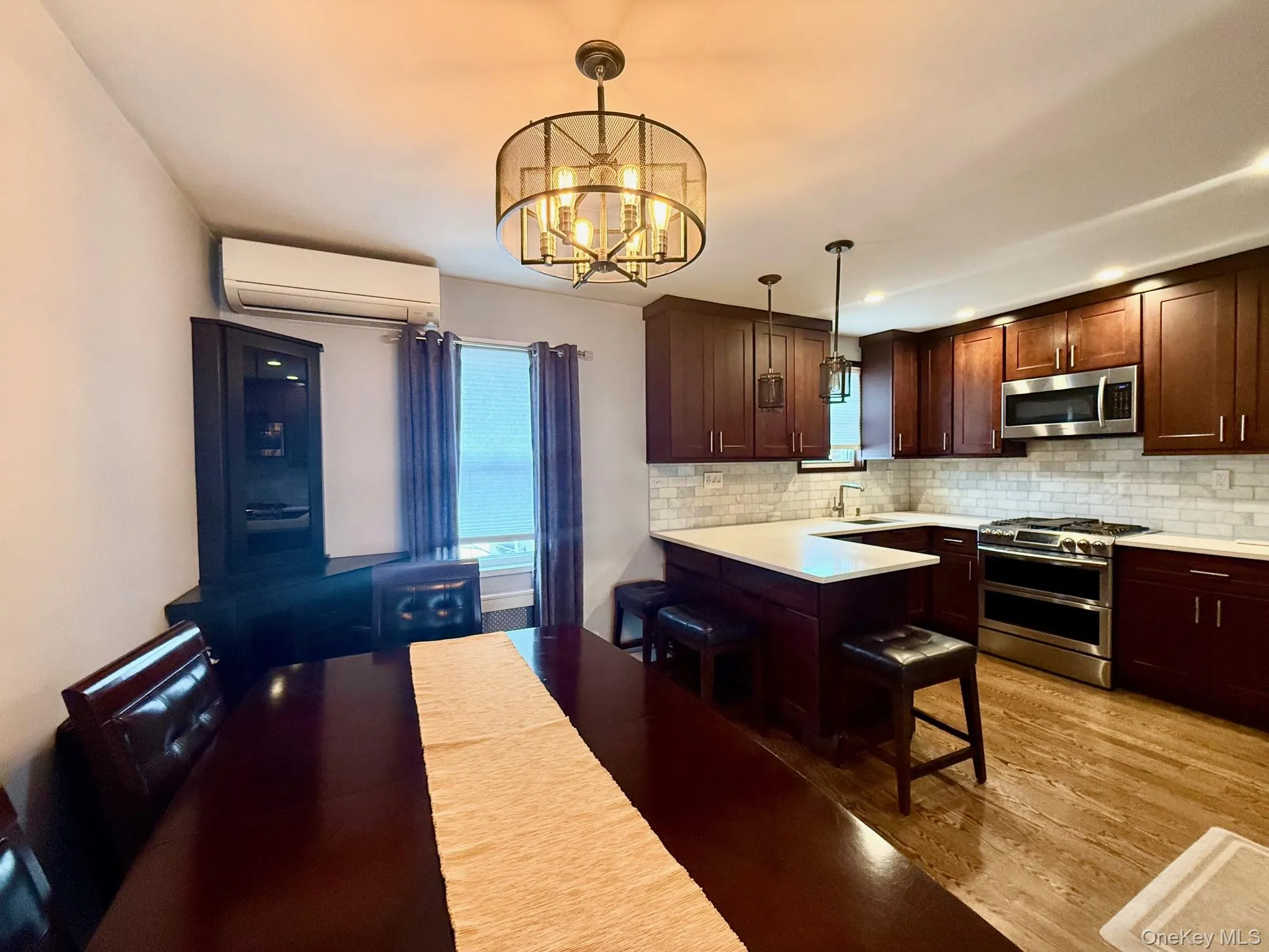 Kitchen featuring decorative backsplash, stainless steel appliances, decorative light fixtures, a breakfast bar area, and a peninsula Kitchen featuring decorative backsplash, stainless steel appliances, decorative light fixtures, a breakfast bar area, and a peninsula