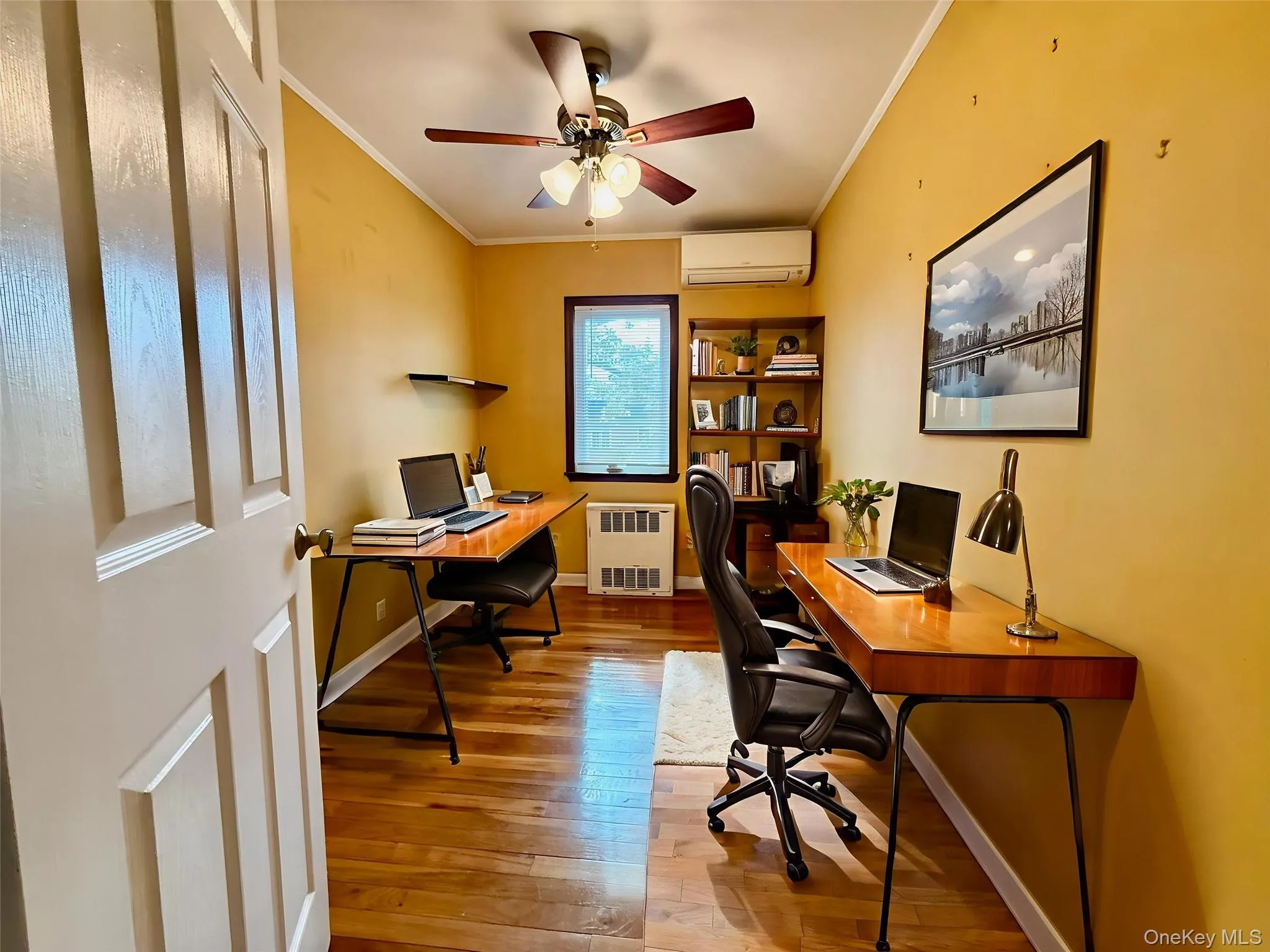 Office space featuring crown molding, light wood finished floors, a ceiling fan, radiator, and an AC wall unit Office space featuring crown molding, light wood finished floors, a ceiling fan, radiator, and an AC wall unit
