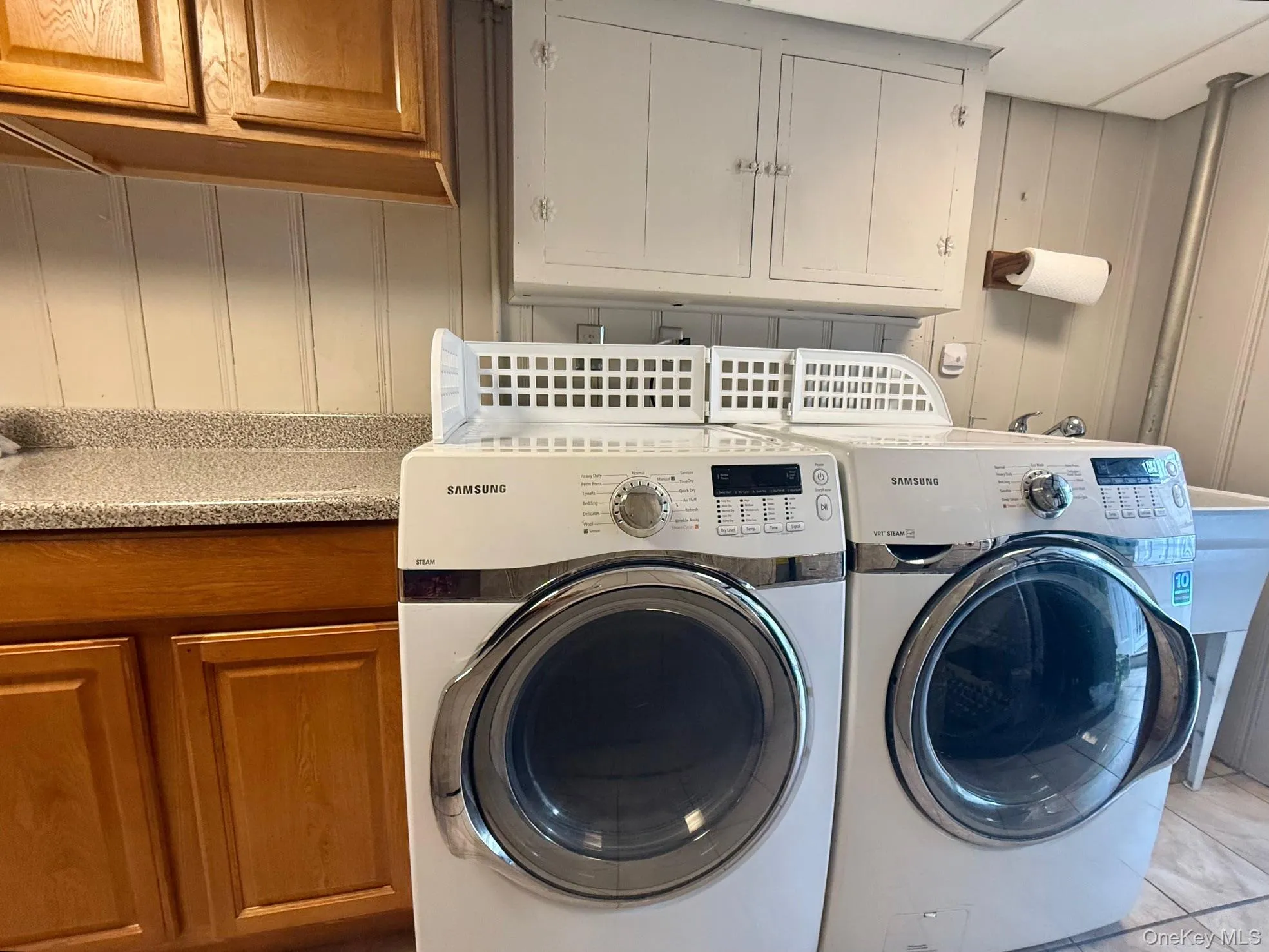 Washroom with cabinet space, washing machine and dryer, and light tile patterned floors Washroom with cabinet space, washing machine and dryer, and light tile patterned floors