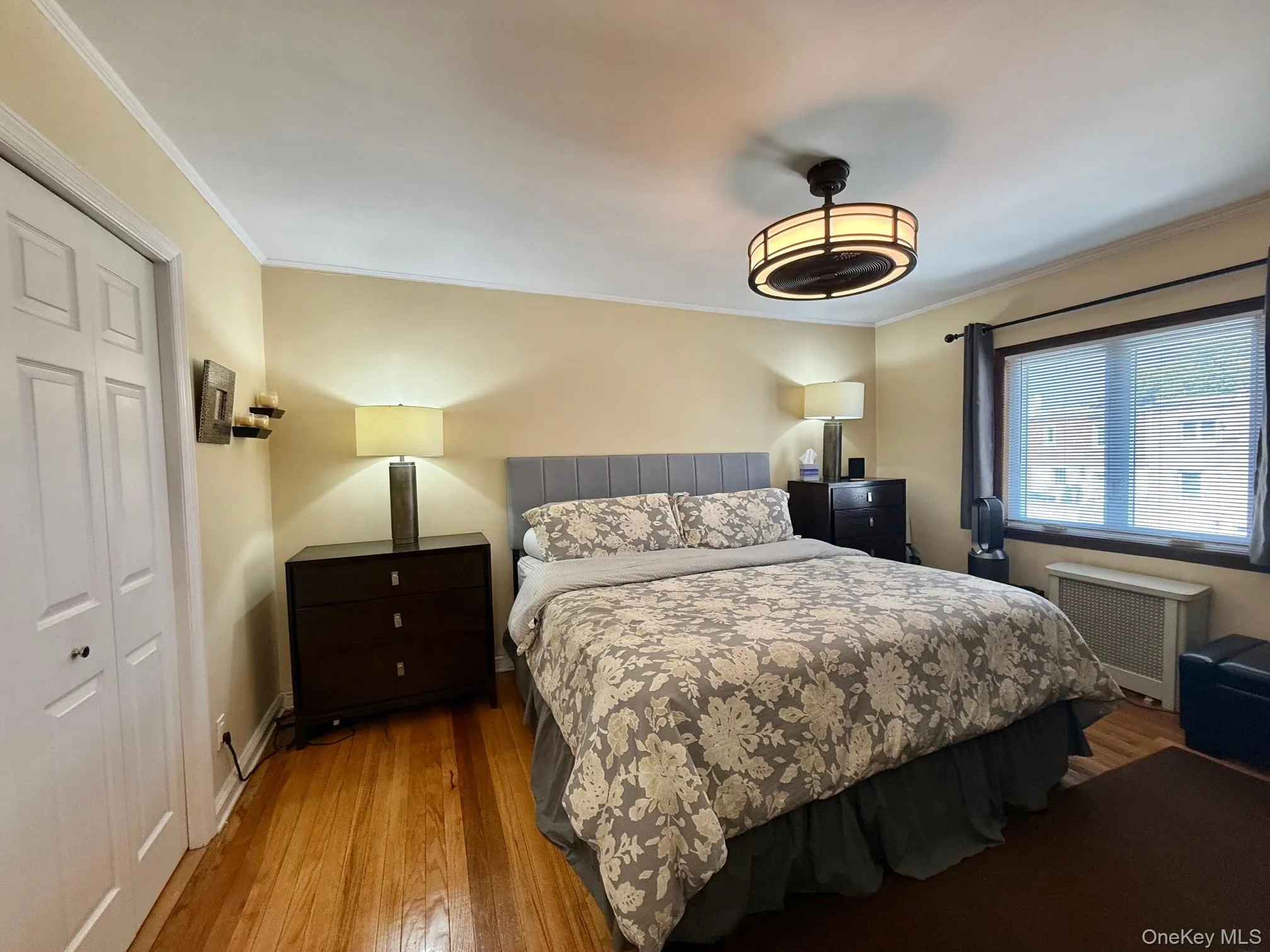 Bedroom featuring a closet, radiator, wood finished floors, and ornamental molding Bedroom featuring a closet, radiator, wood finished floors, and ornamental molding