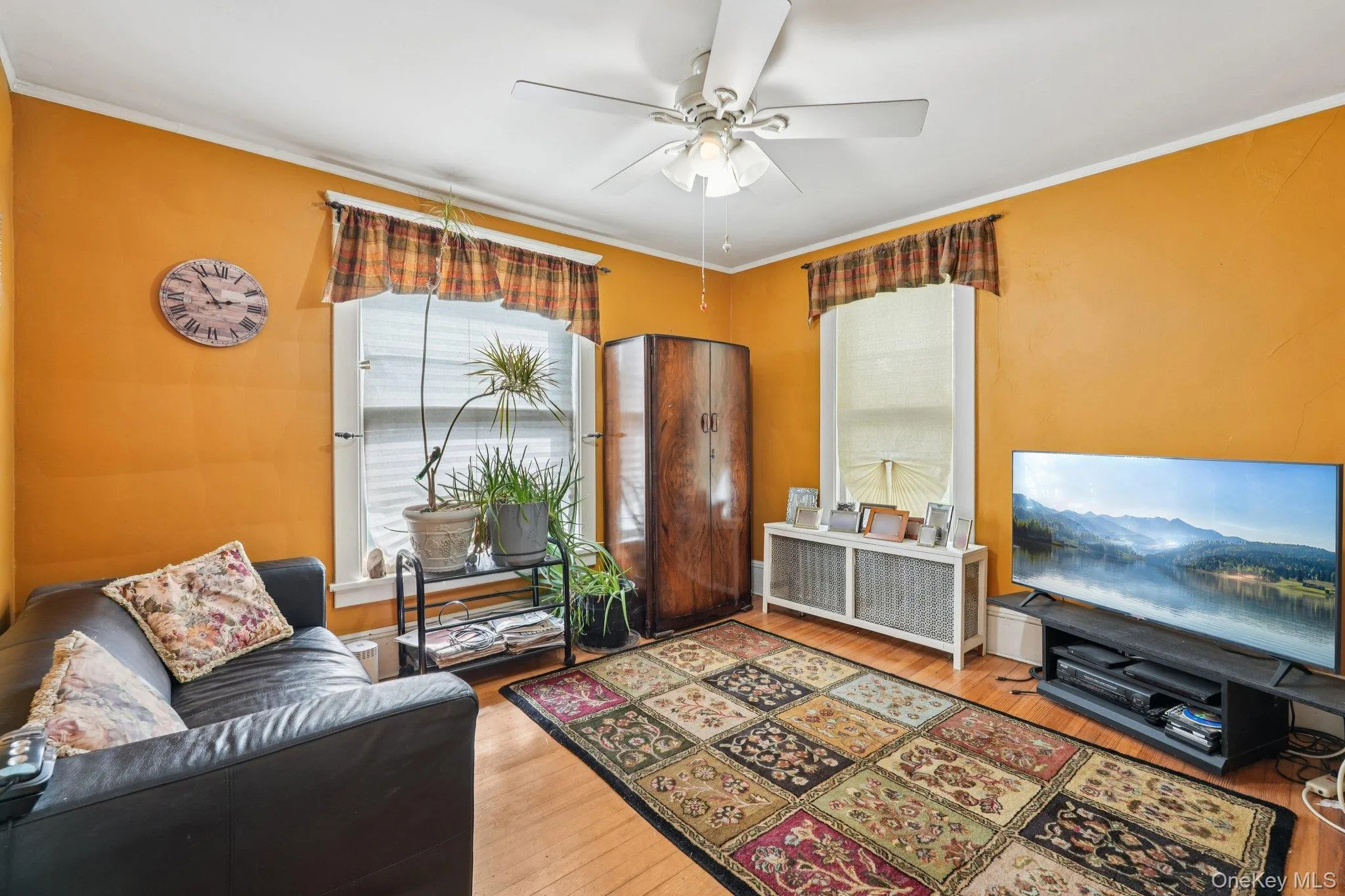 Living area with ornamental molding, radiator, hardwood / wood-style floors, and a ceiling fan Living area with ornamental molding, radiator, hardwood / wood-style floors, and a ceiling fan